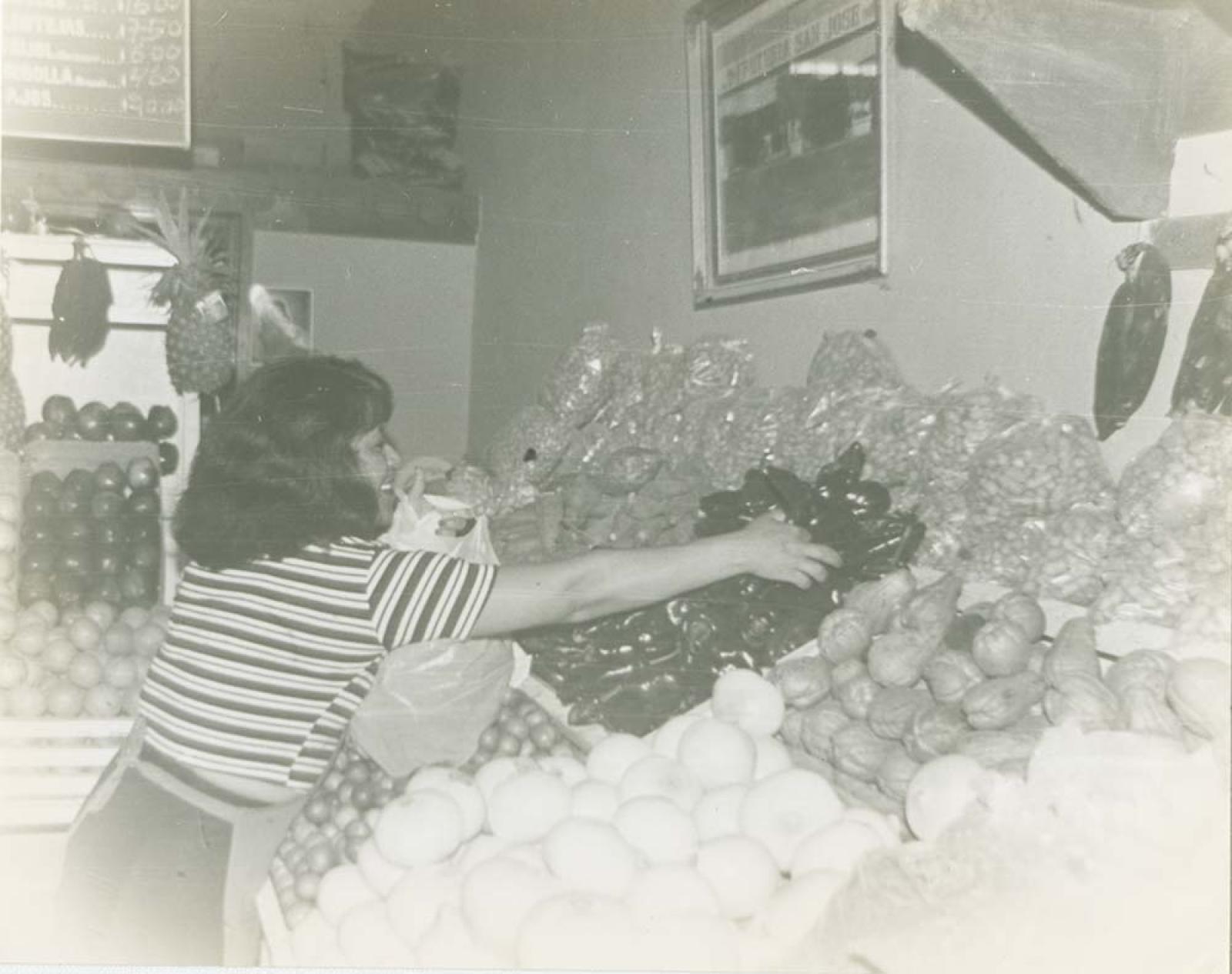 Mujer en puesto de frutas y verduras.