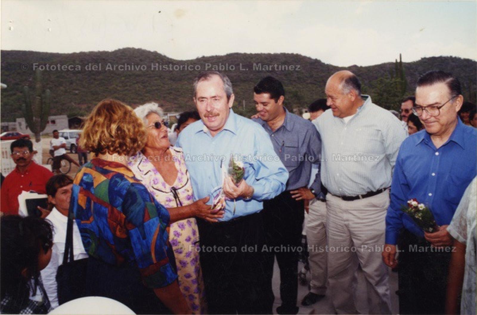Mujer entrega ramo de flores a Leonel Cota Montaño, en reunión con simpatizantes.