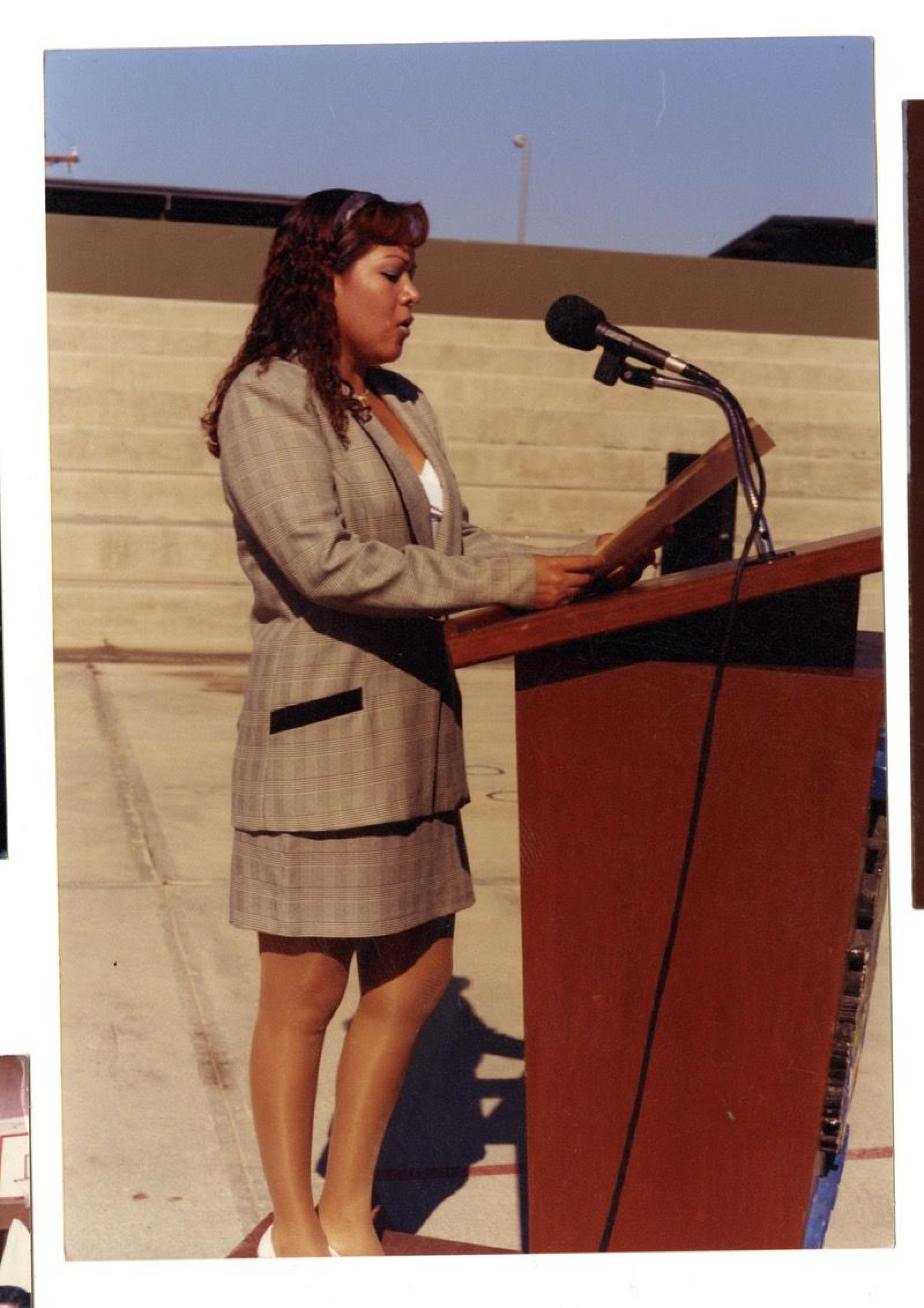 Mujer expone discurso en atril.