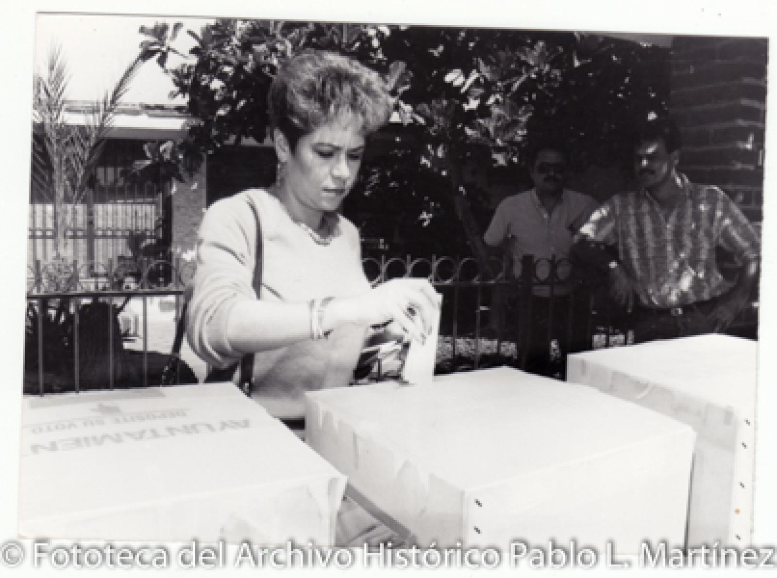 Mujer que emite su voto en urna.