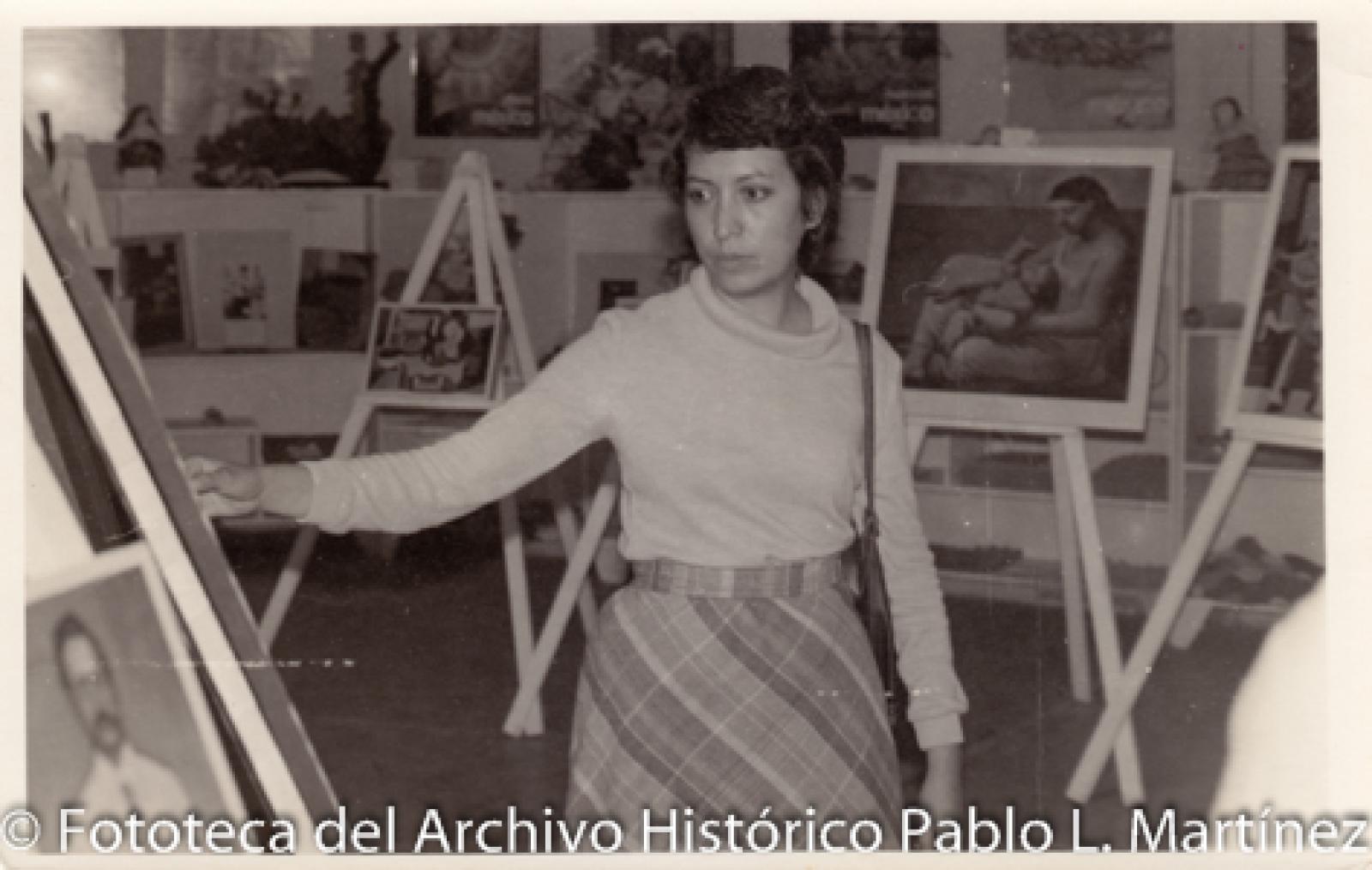 Mujer que observa pinturas montadas en caballetes