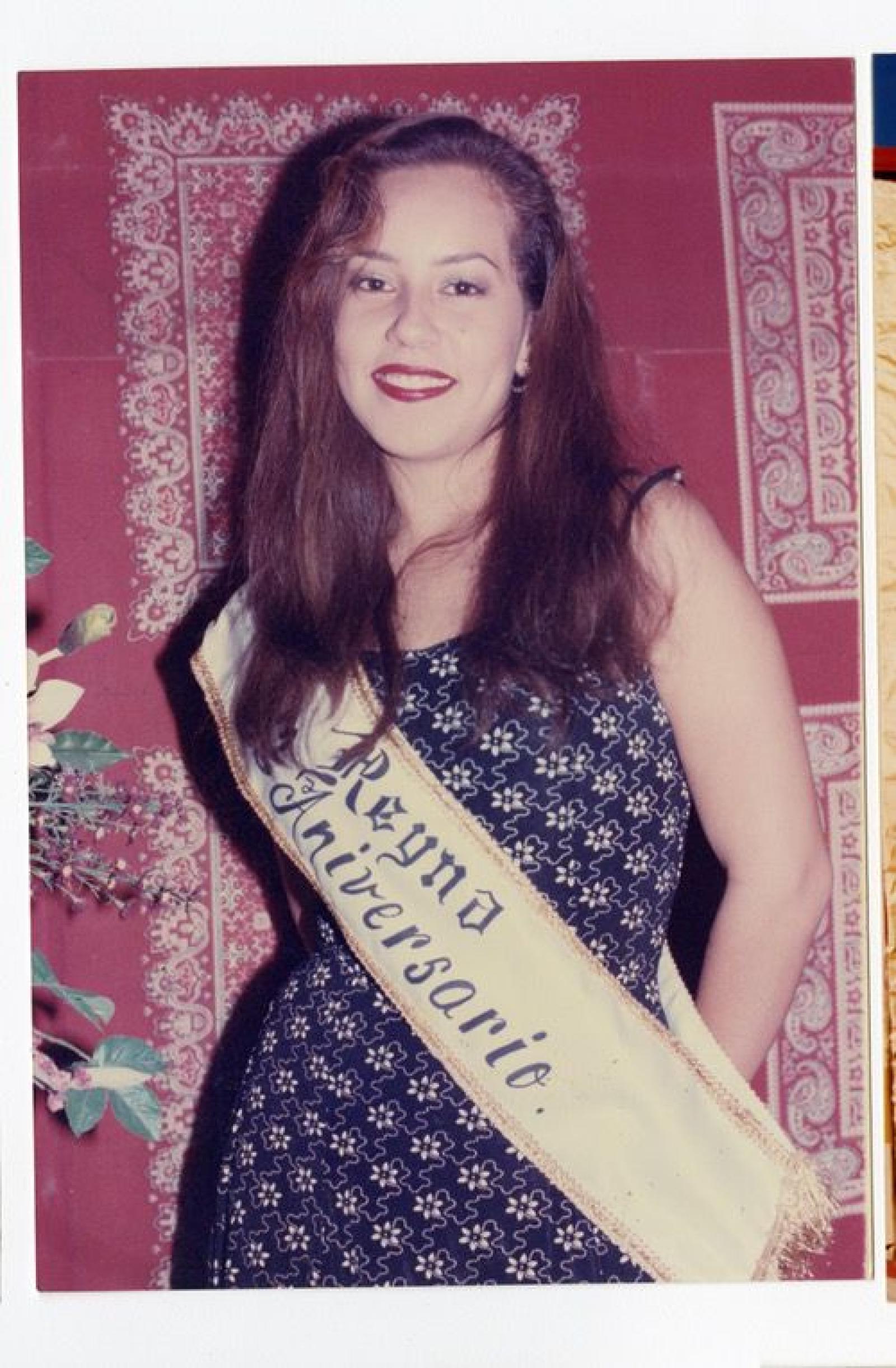 Mujer que porta una banda con la inscripción “Reyna Aniversario”