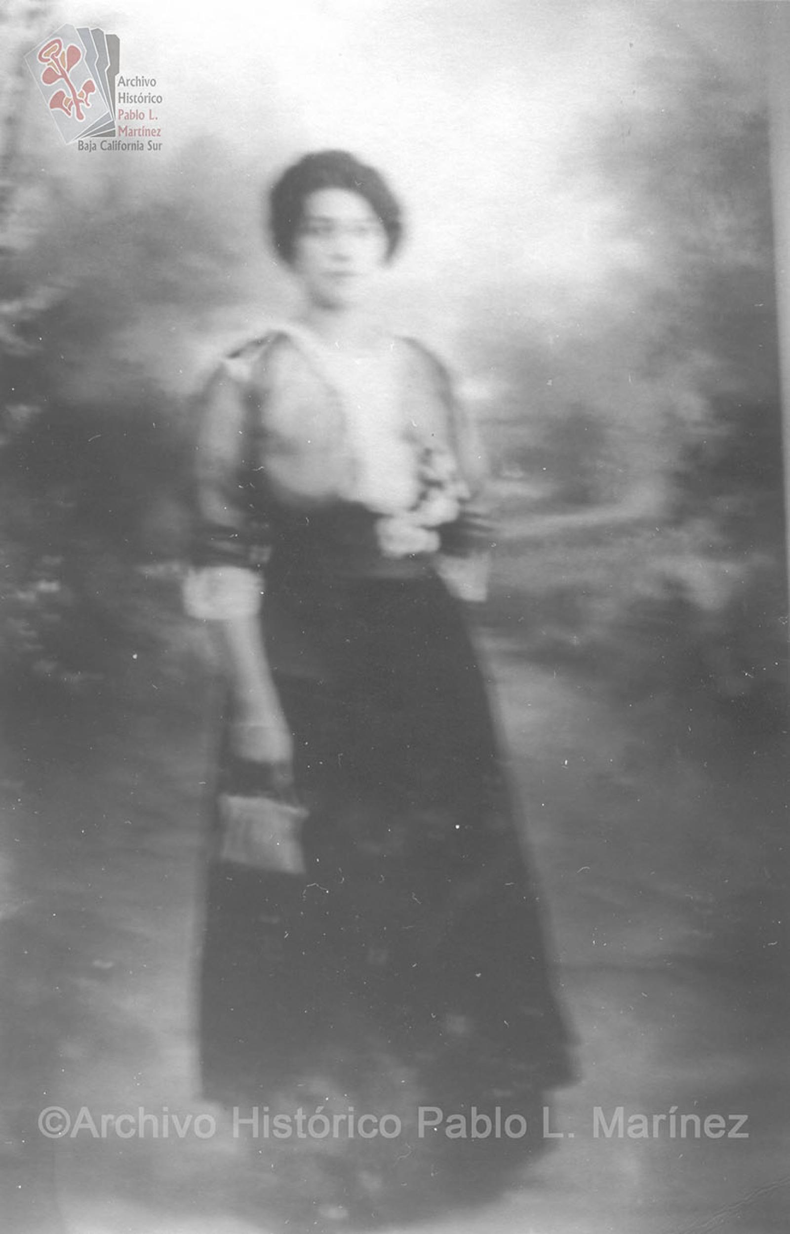 Mujer que posa de pie, viste elegante.