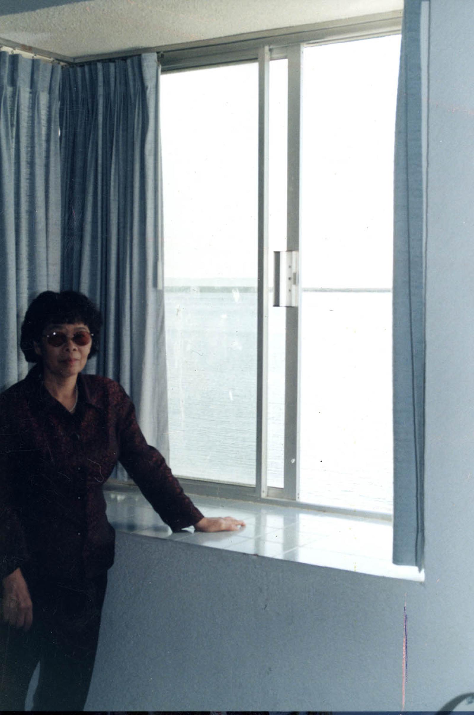 Mujer que posa junto a ventana.