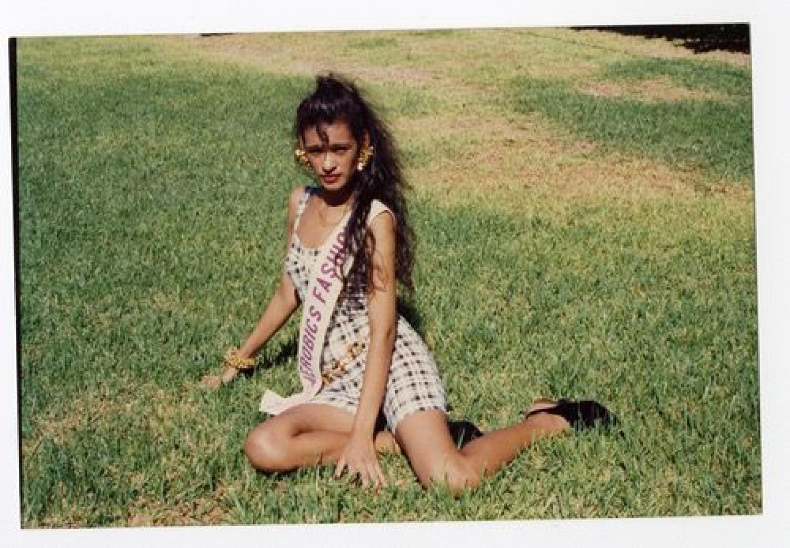 Mujer que posa sentada en césped.