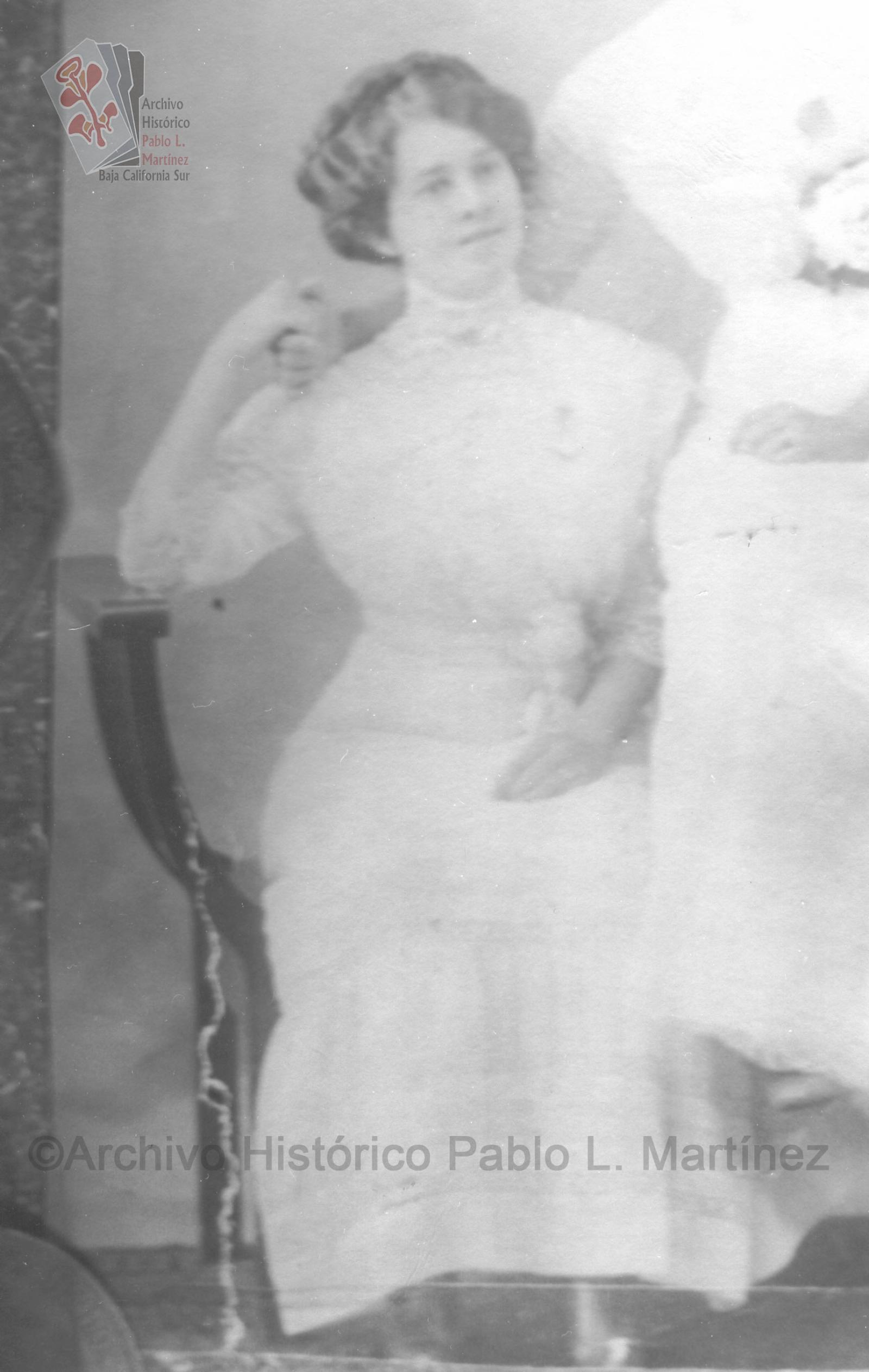 Mujer que posa sentada y viste elegante de color blanco.
