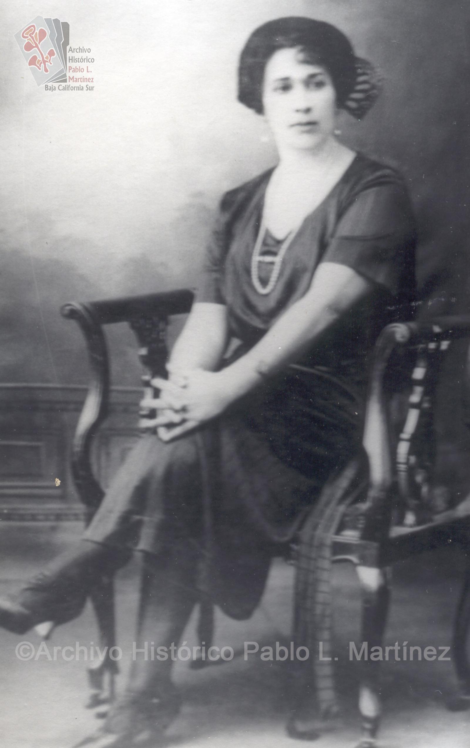 Mujer sentada con manos entrelazadas.