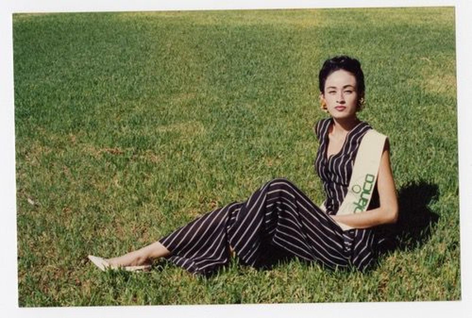 Mujer sentada en césped.