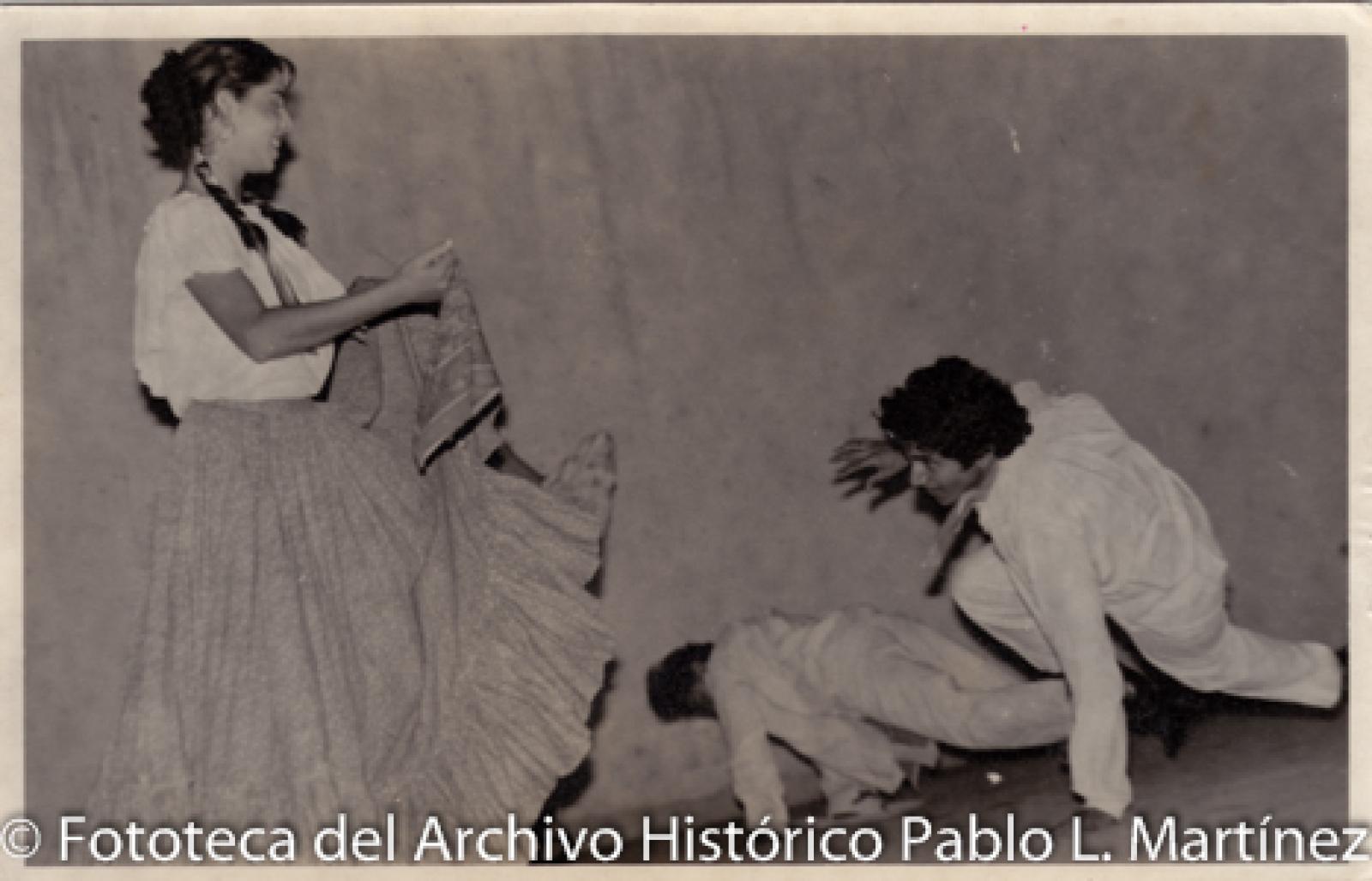 Mujer y hombres que ejecutan danza típica mexicana.