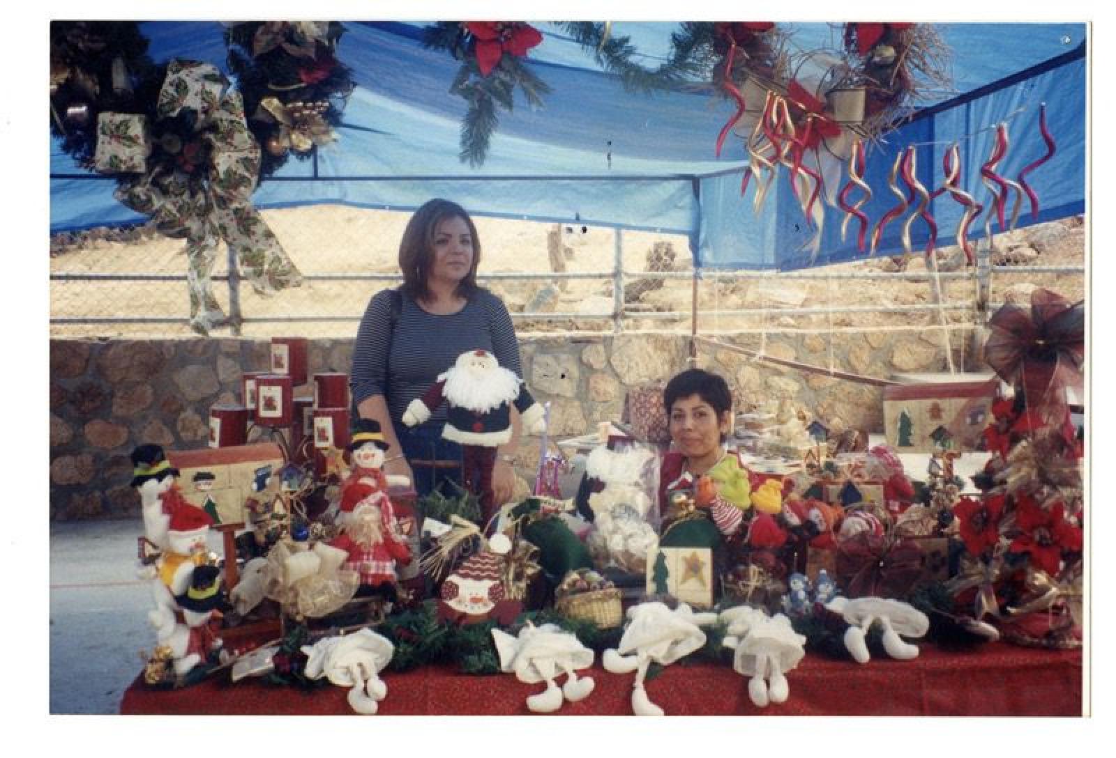 Mujeres en puesto con adornos navideños.
