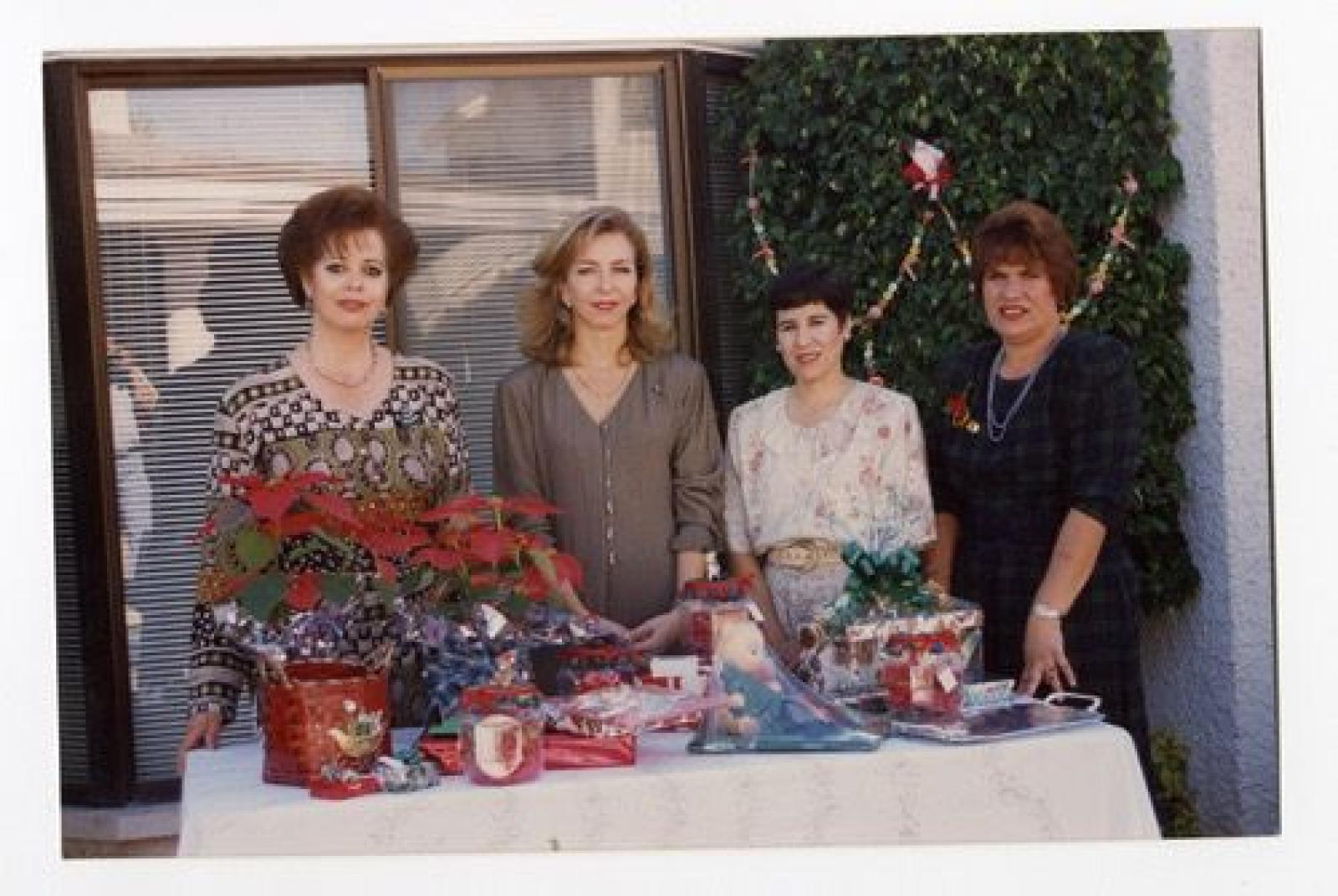Mujeres frente a mesa de regalos de navidad, retrato de grupo.