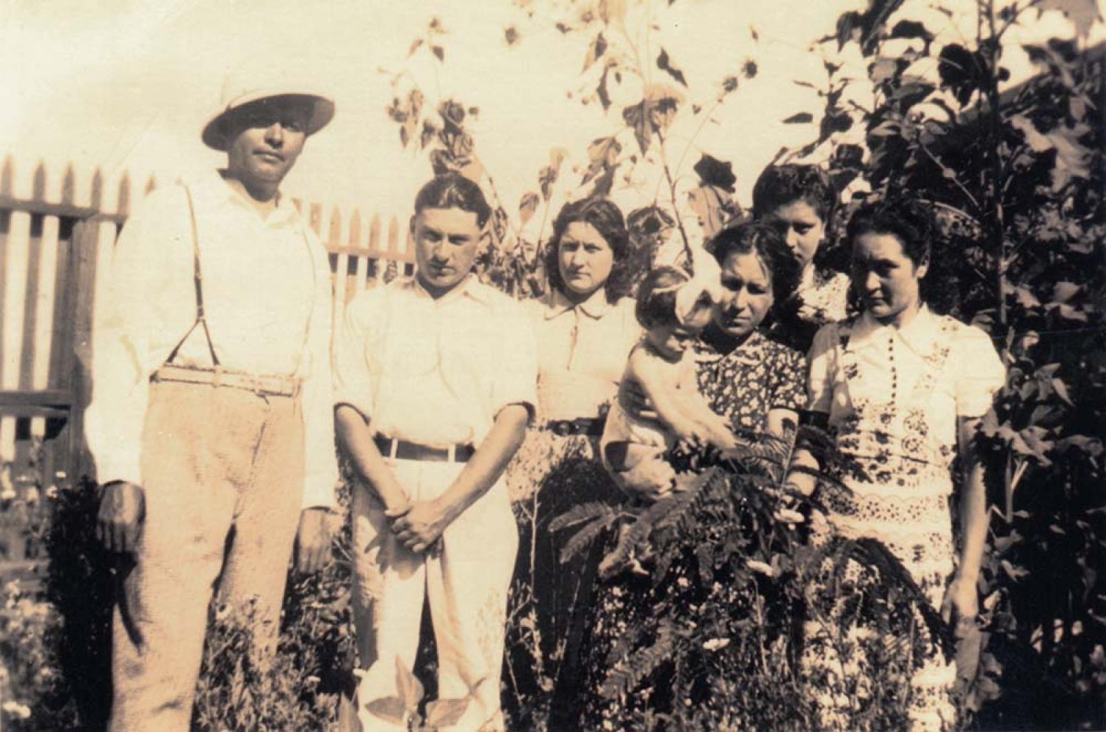 Mujeres, hombres y niña posan en jardín, retrato de grupo.