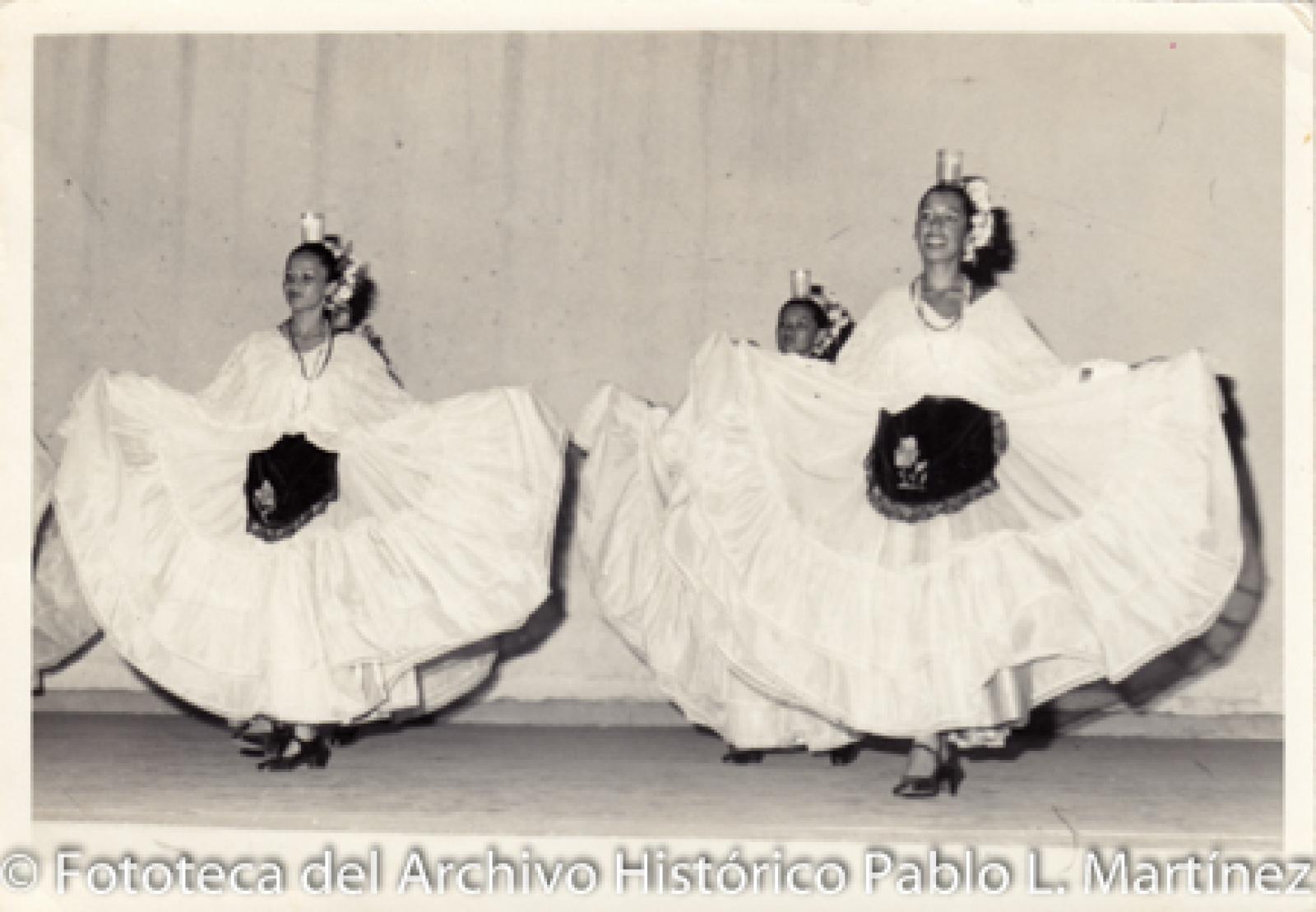 Mujeres que bailan con veladoras sobre la cabeza.