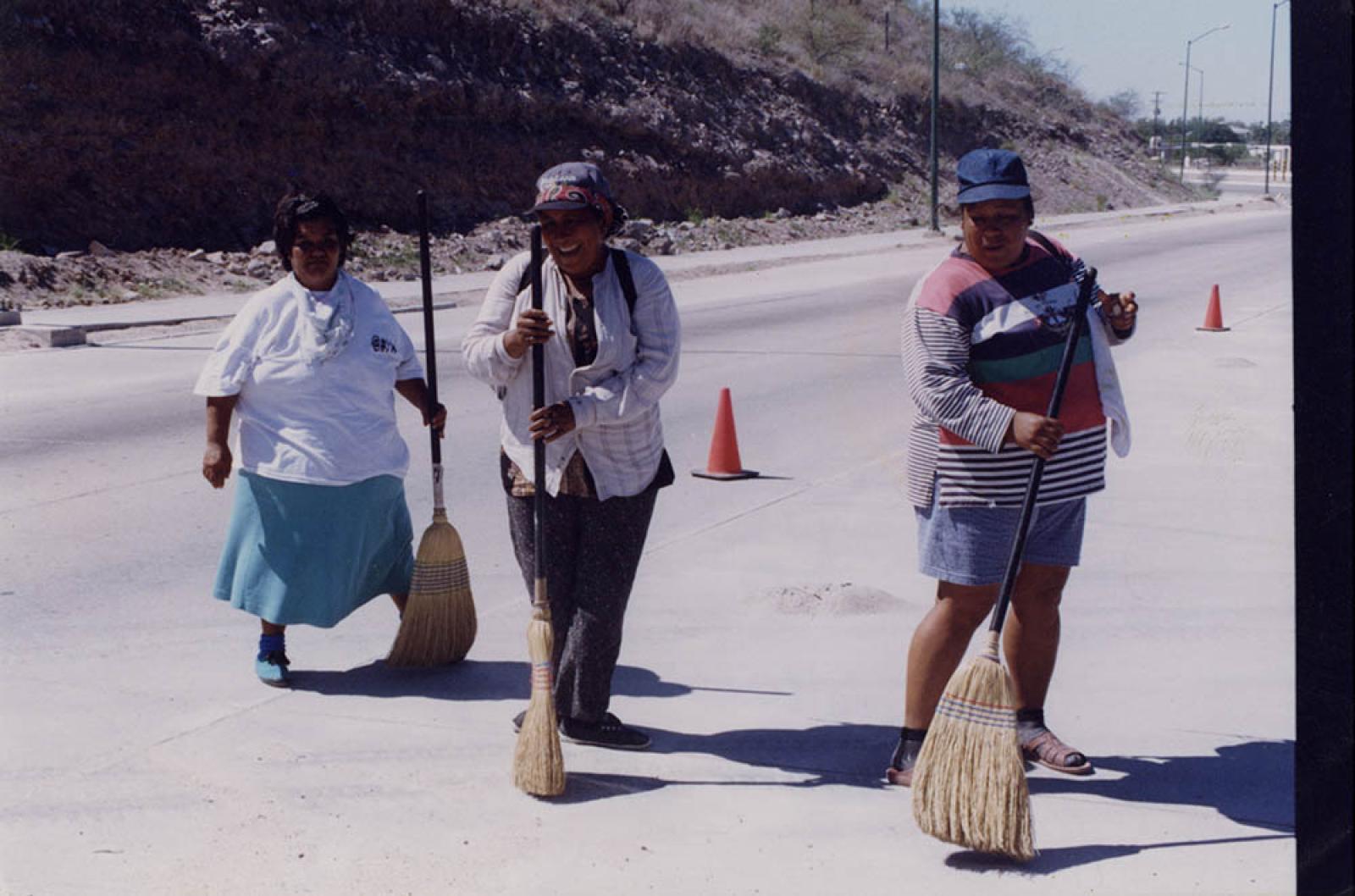 Mujeres que trabajan en limpieza de vías públicas.