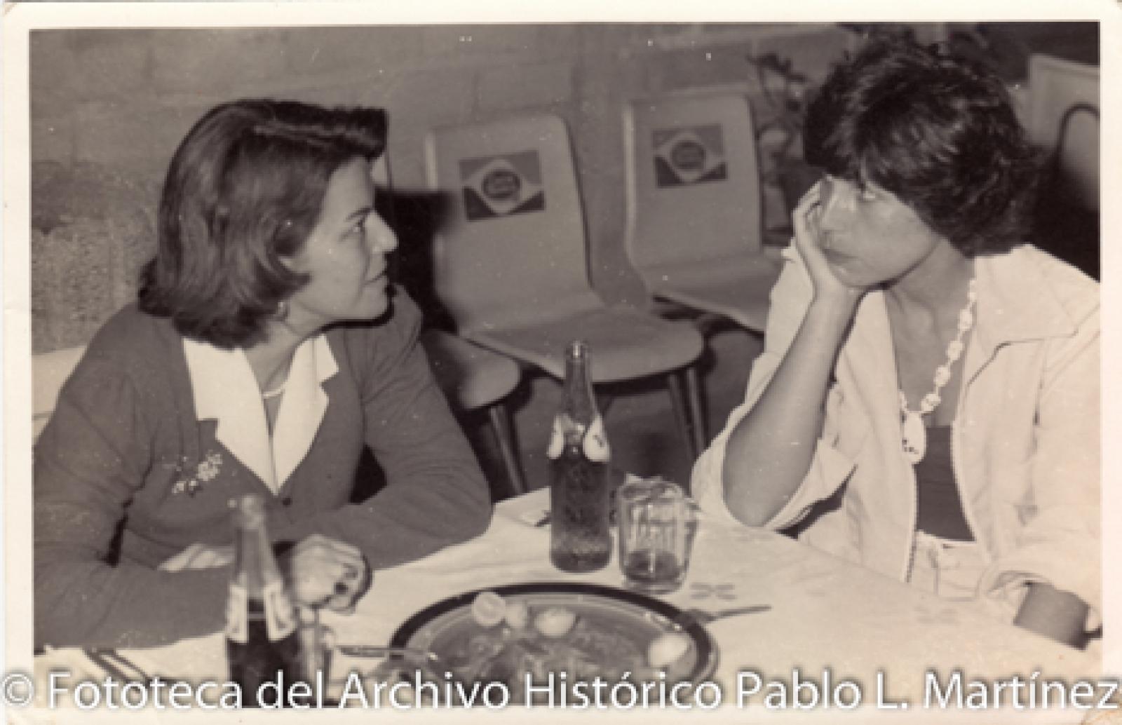 Mujeres sentadas frente a mesa con alimentos
