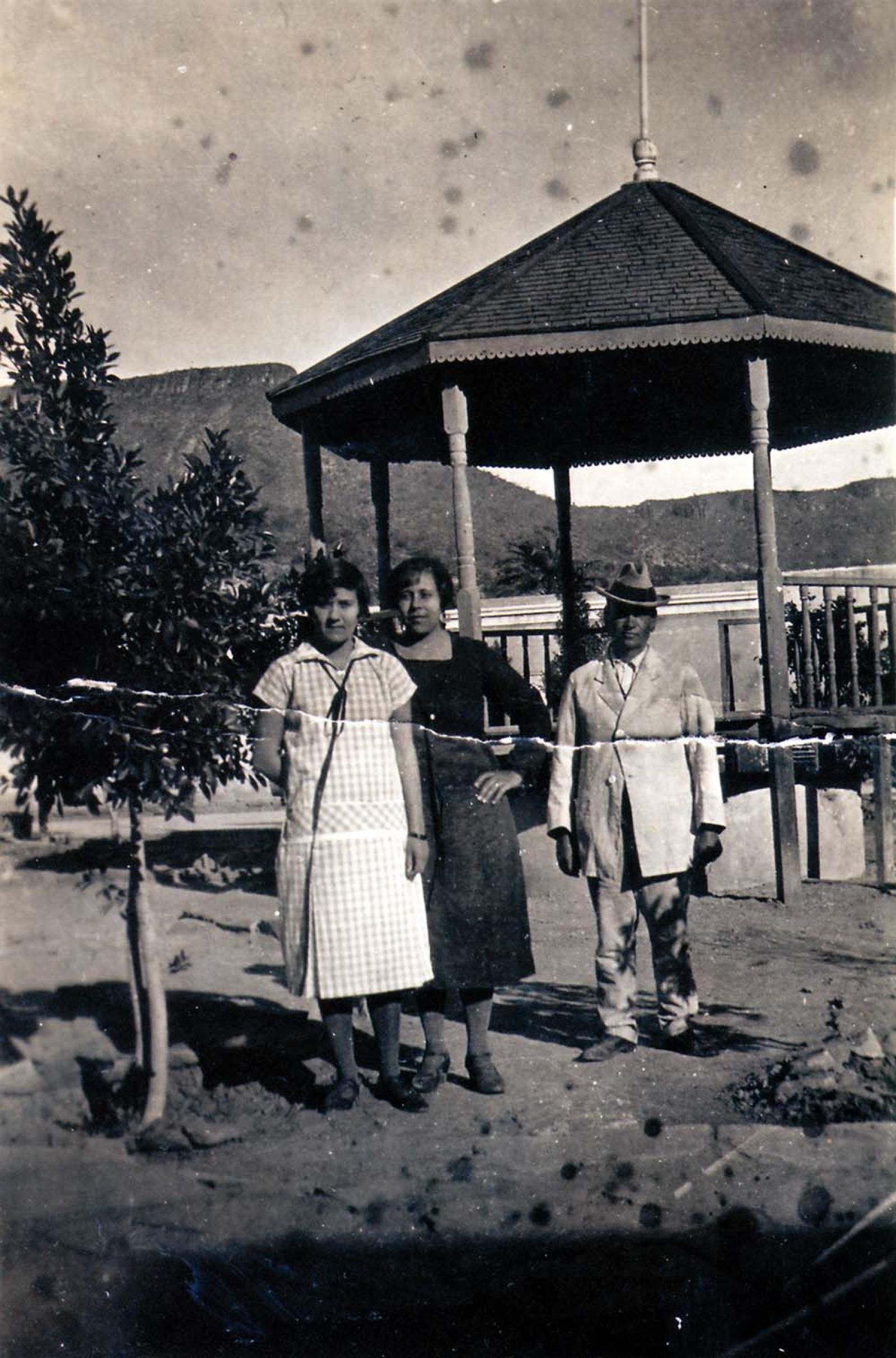 Mujeres y hombre posan frente a kiosco.