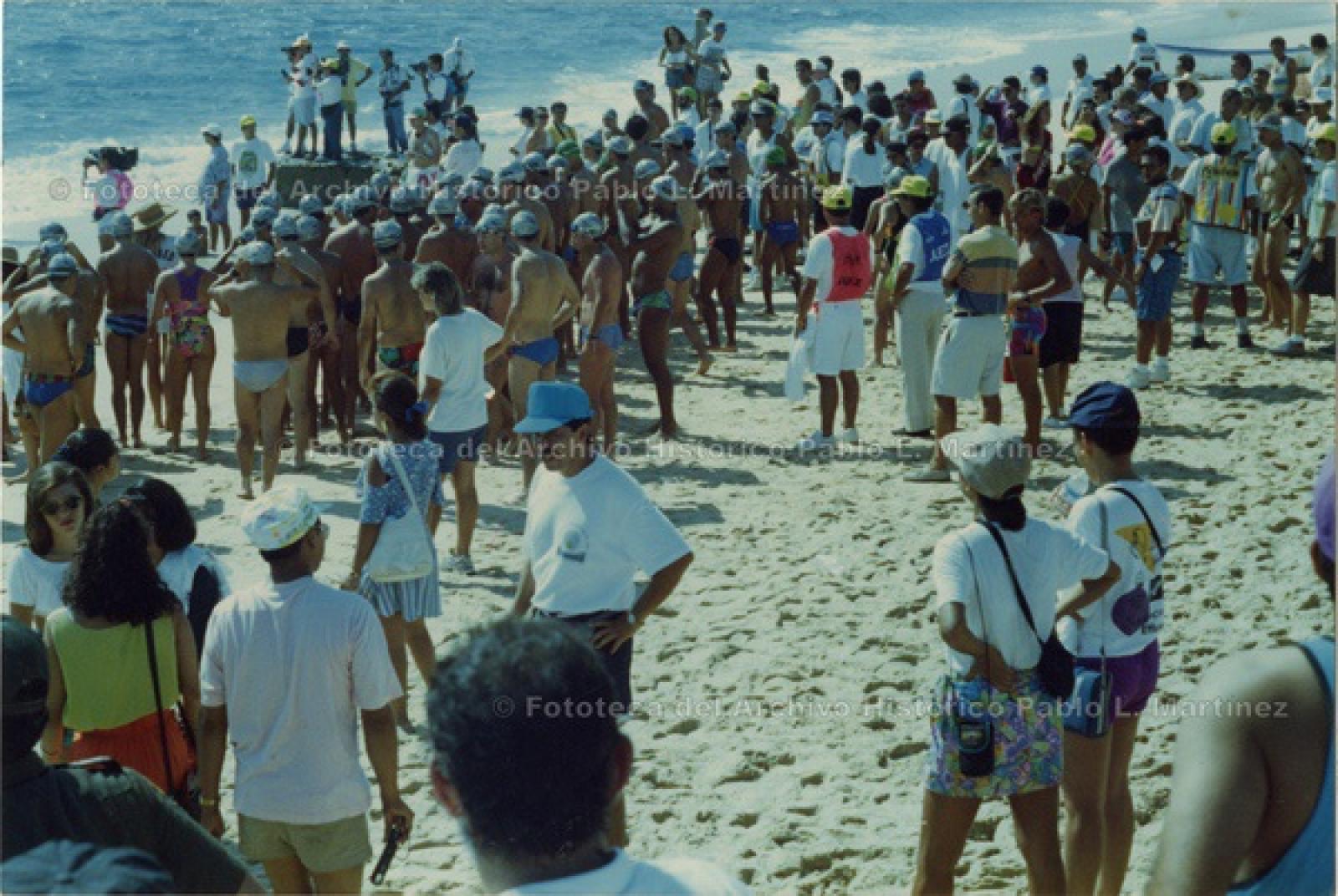 Nadadores y espectadores en playa.