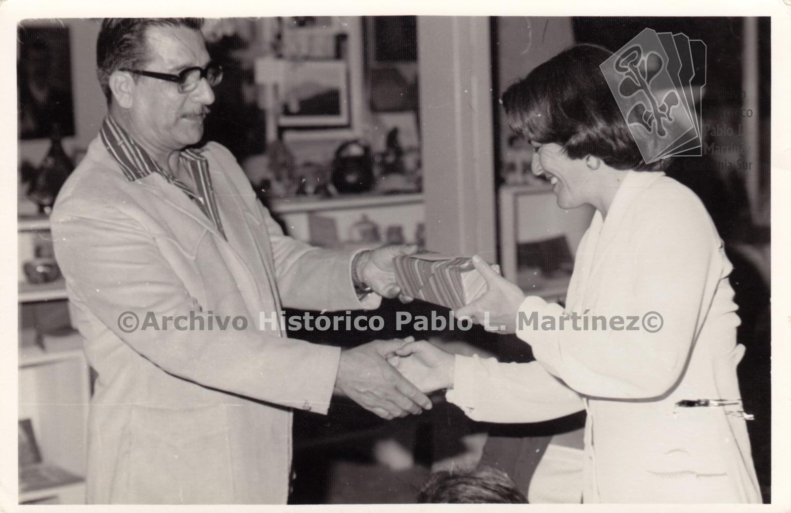 Néstor Agúndez Martínez, entrega obsequio a mujer.