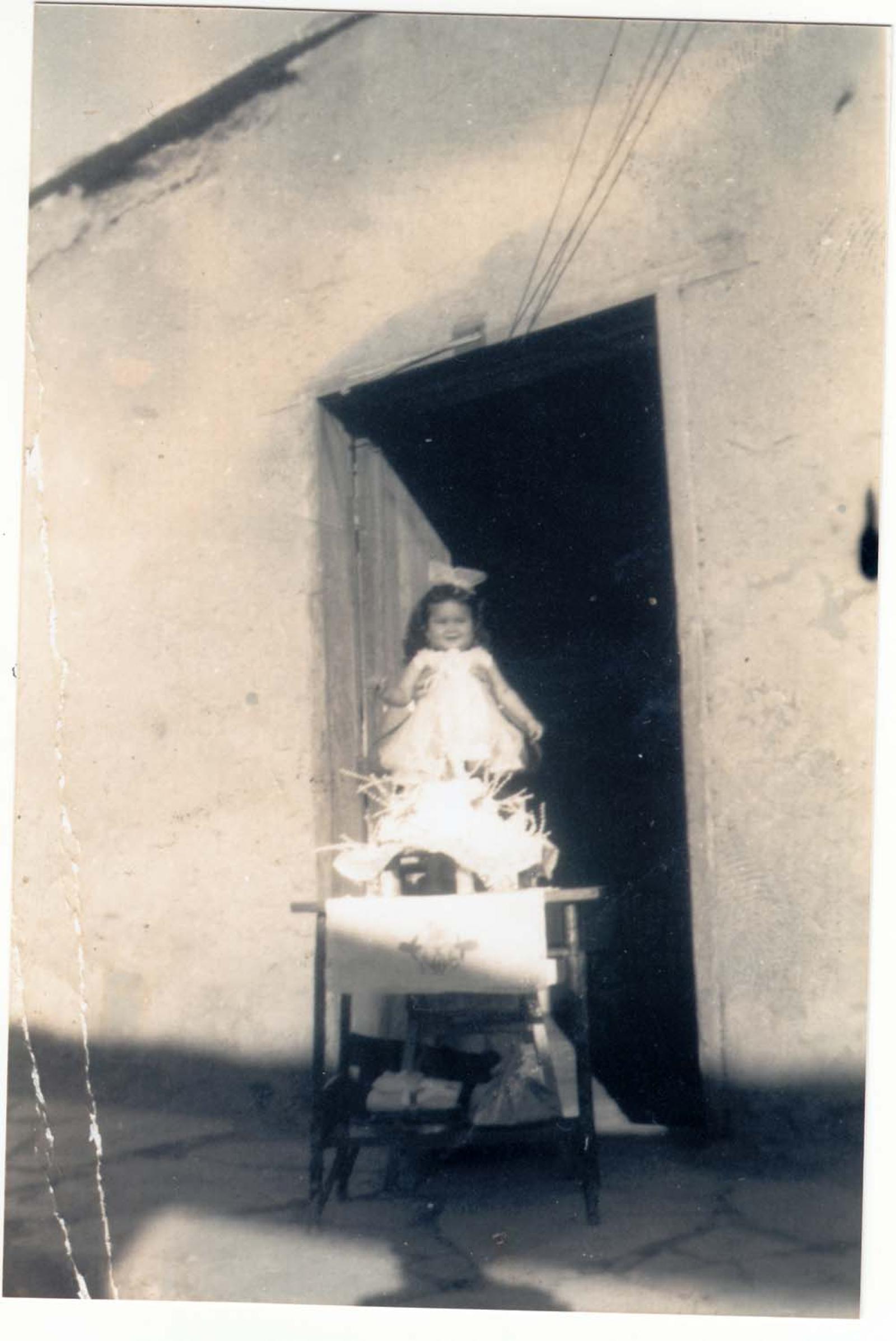 Niña con pastel frente a una puerta.