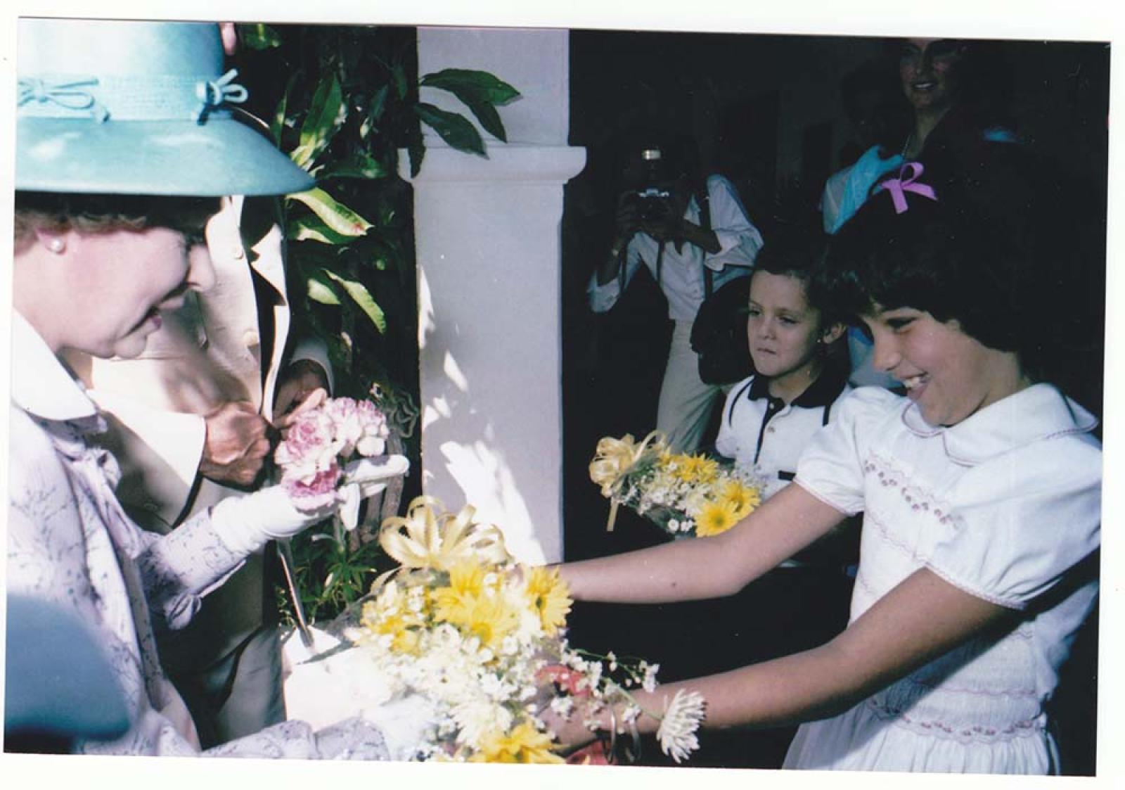 Niña entrega flores a la reina Isabel II.