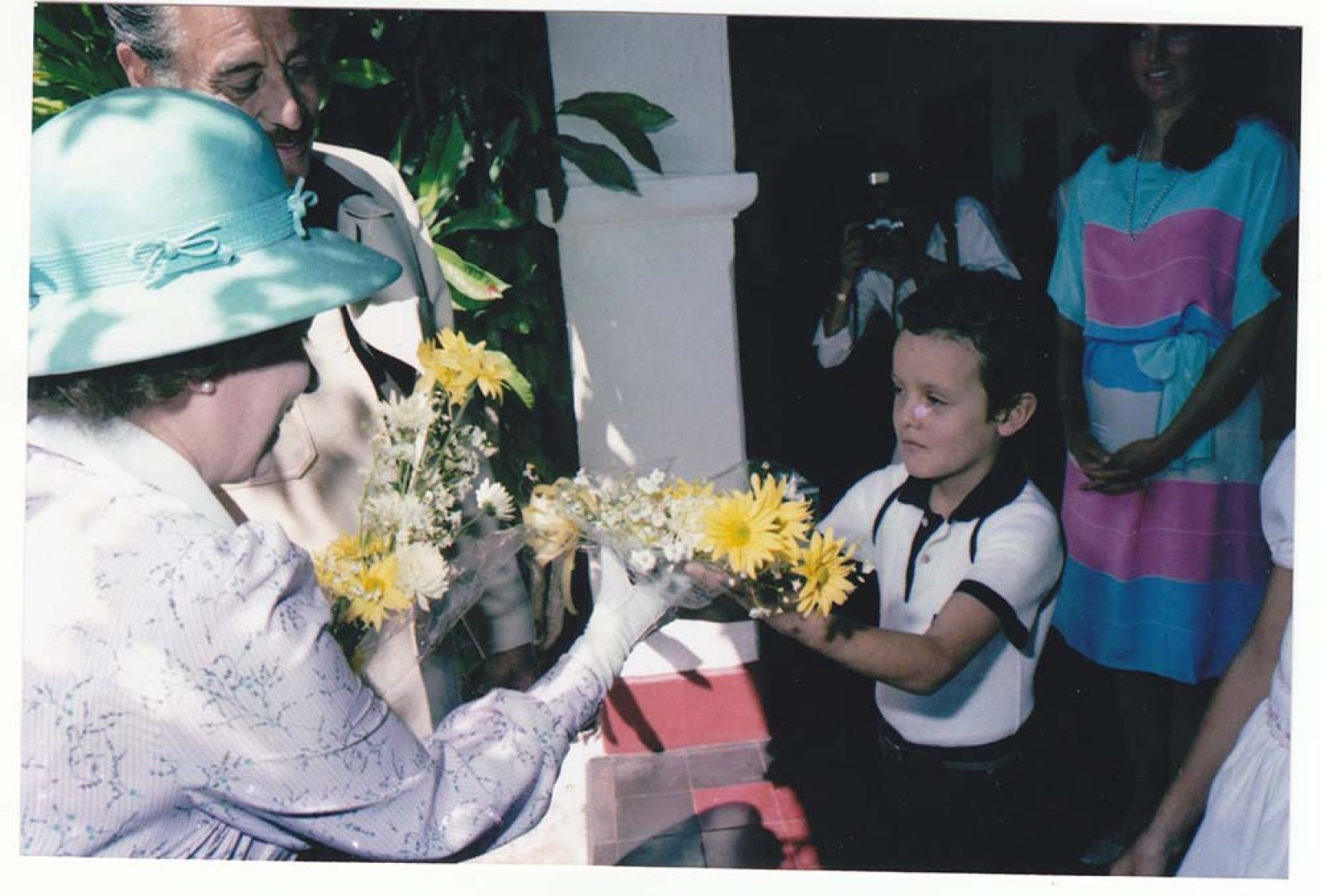 Niño entrega flores a la reina Isabel II.