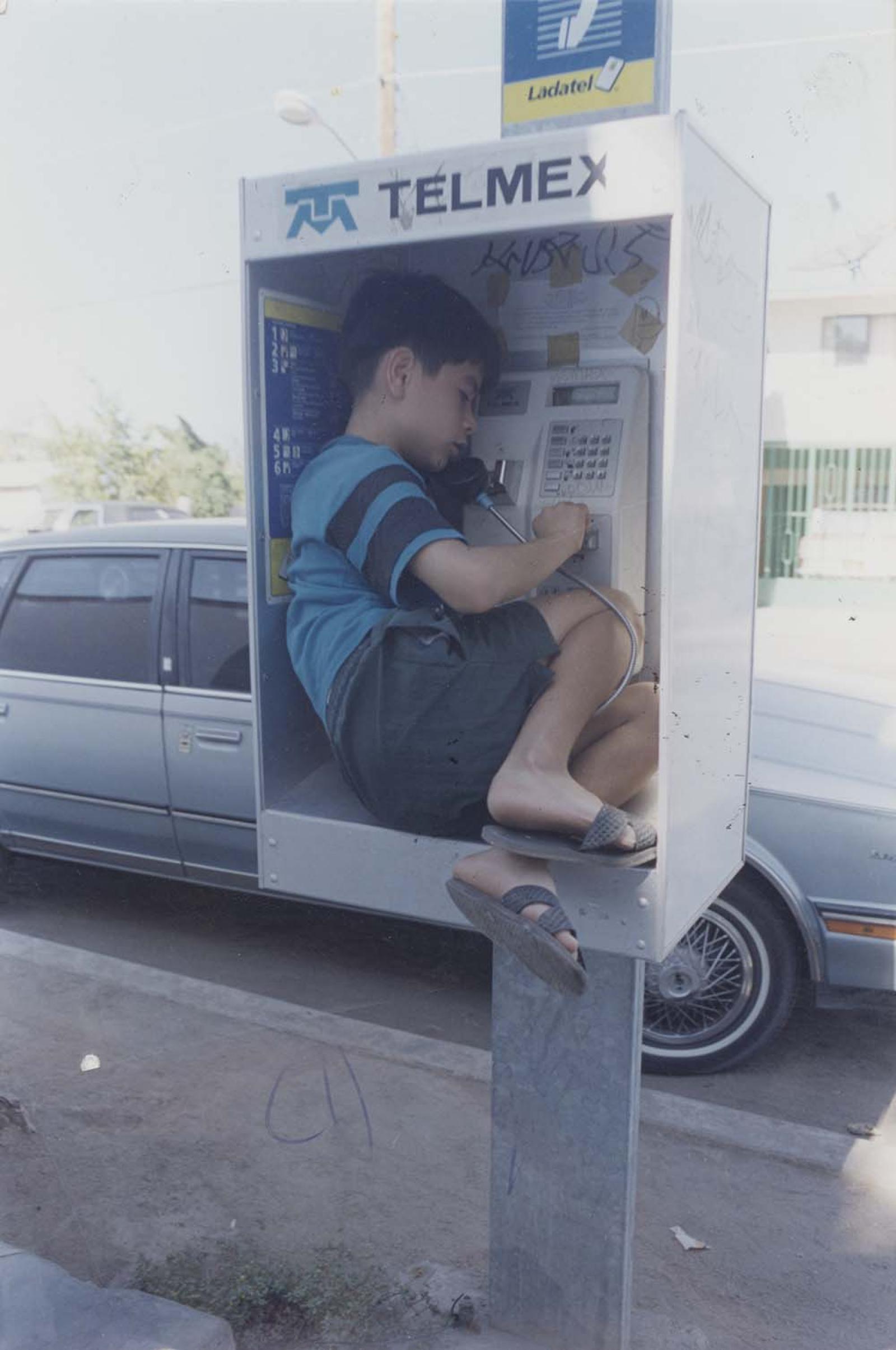 Niño habla por teléfono desde el interior de caseta.