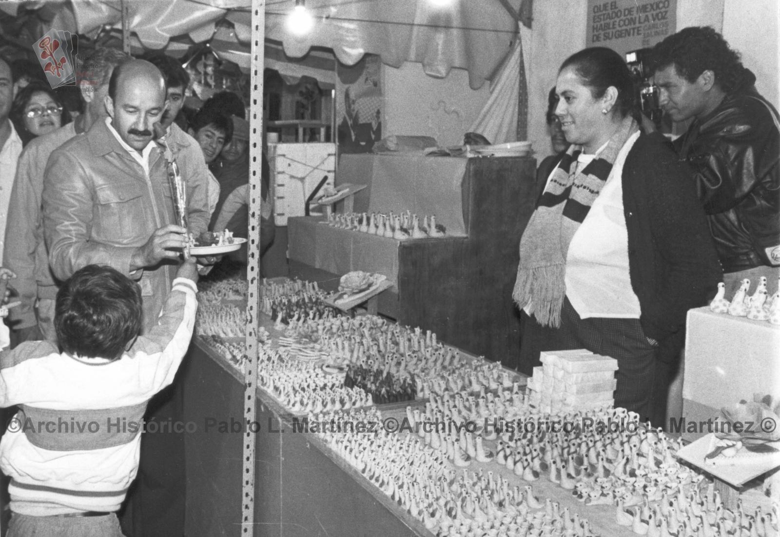 Niño regala una rosa a Carlos Salinas de Gortari frente a puesto de artesanías.