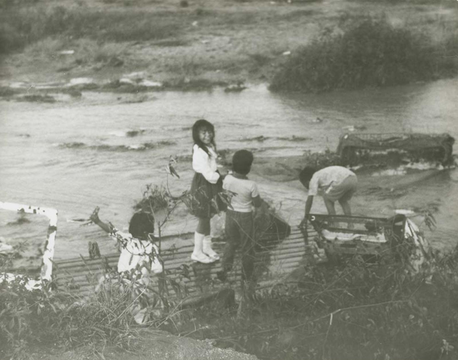 Niños en arroyo crecido.
