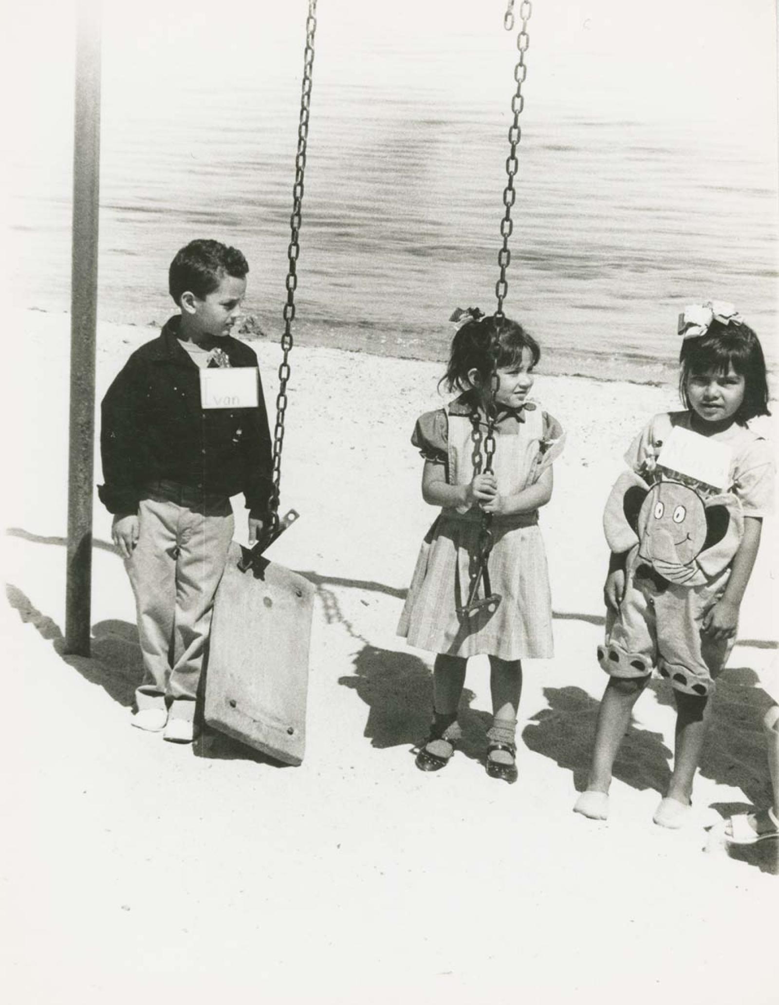 Niños en columpios frente al mar.