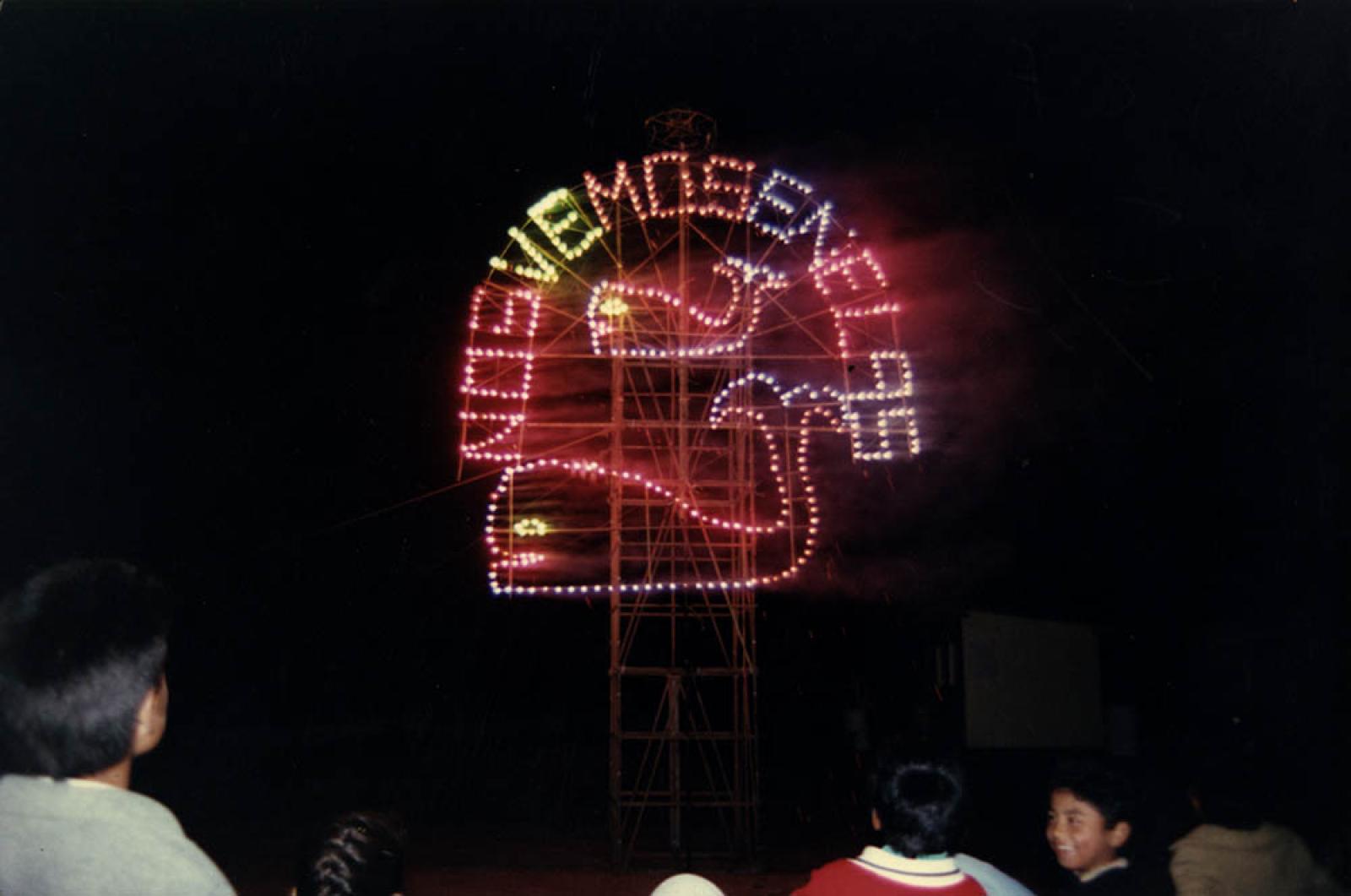 Niños frente a figuras de ballenas adornadas con luces de colores.