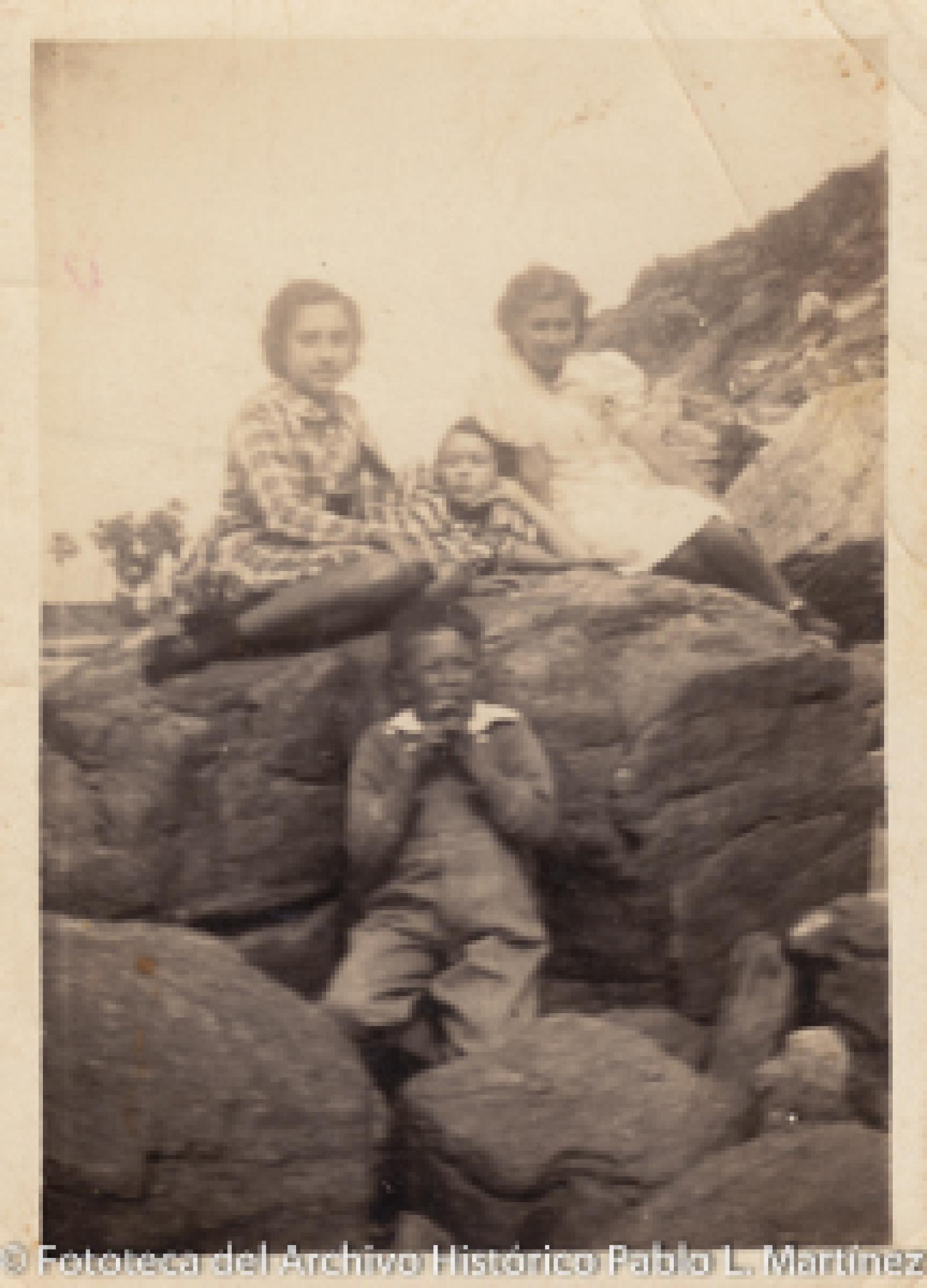Niños que se sientan en rocas.