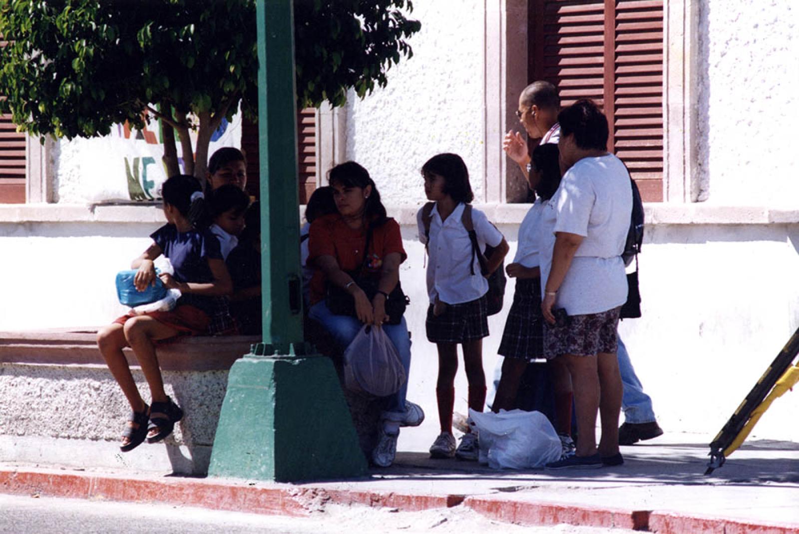 Niños y adultos se refugian a la sombra de árbol, frente a la antigua Casa de Gobierno de La Paz.