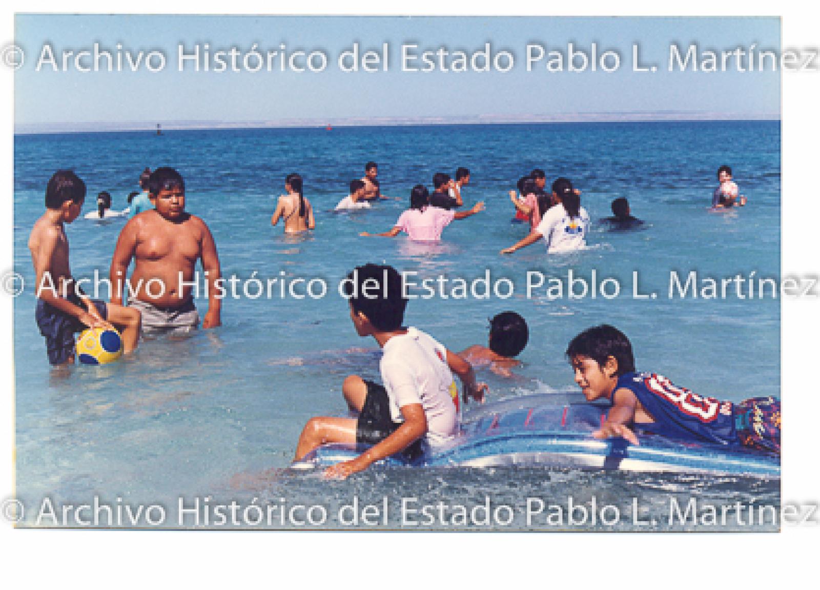 Niños y niñas se bañan en playa.