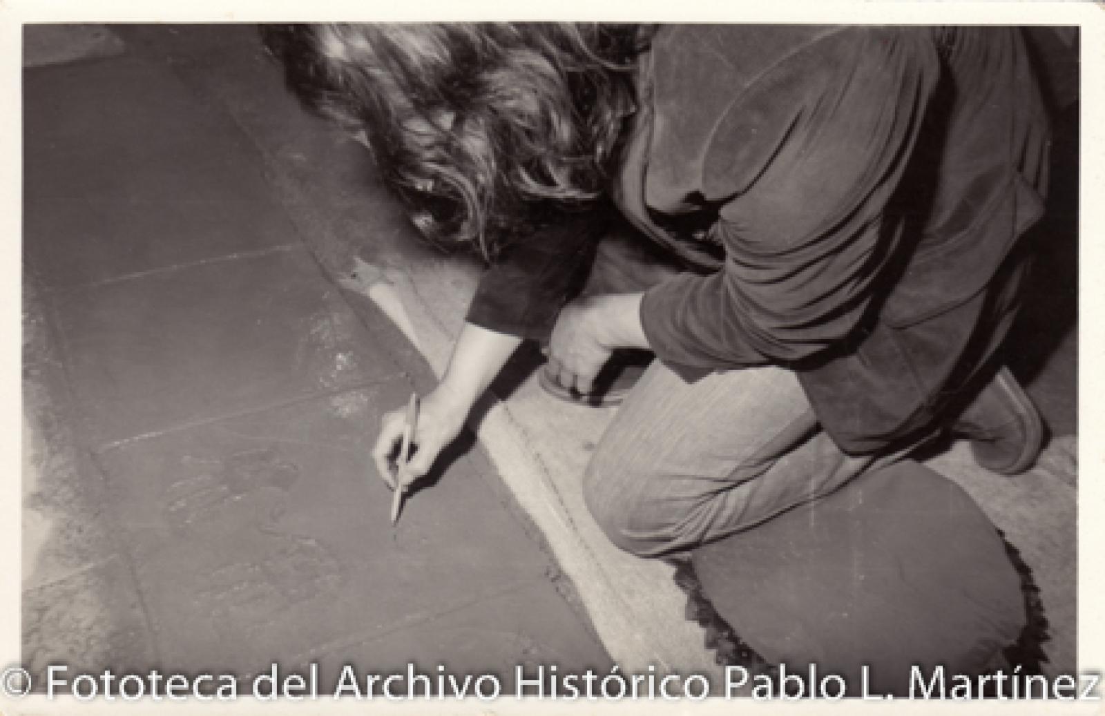 Persona que escribe sobre cemento fresco.