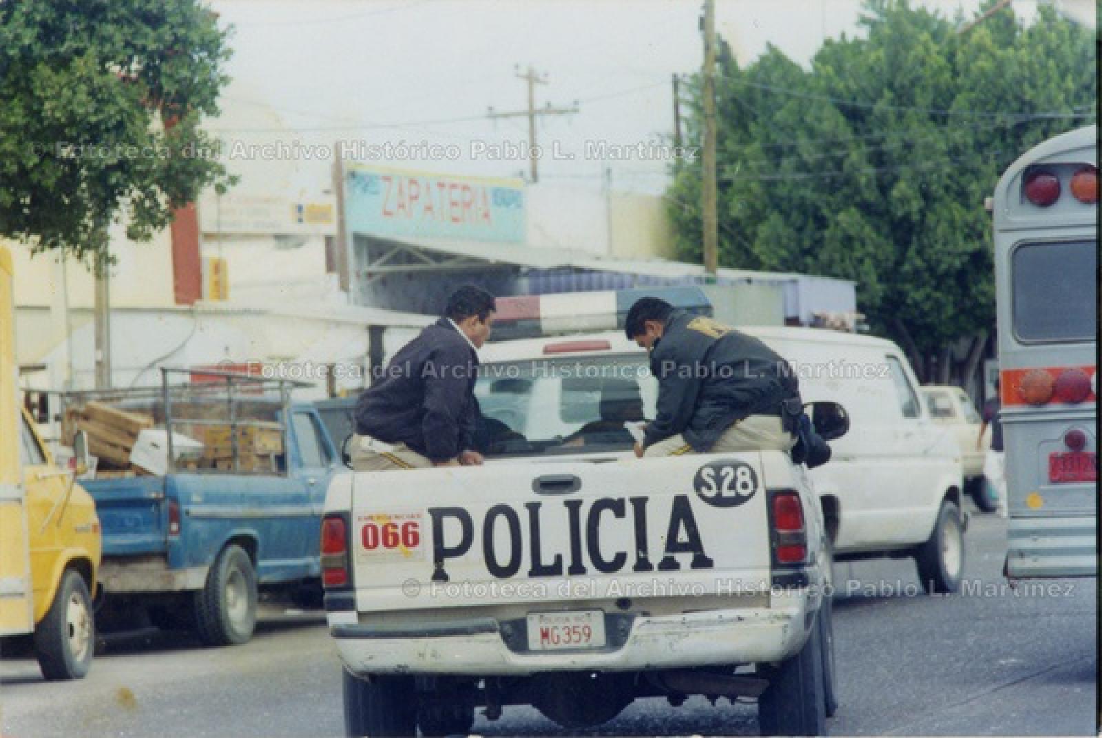 Policías sentados en parte trasera de patrulla tipo pick-up.