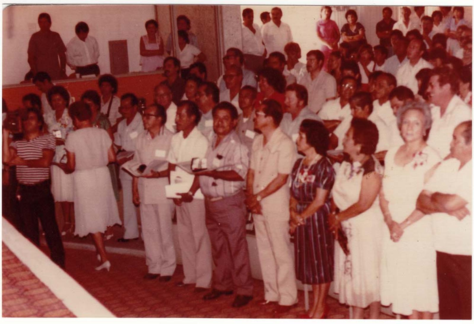 Público de pie en auditorio.