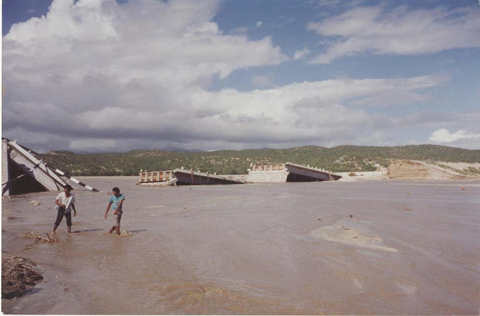 Puente vial derrumbado, sobre arroyo.