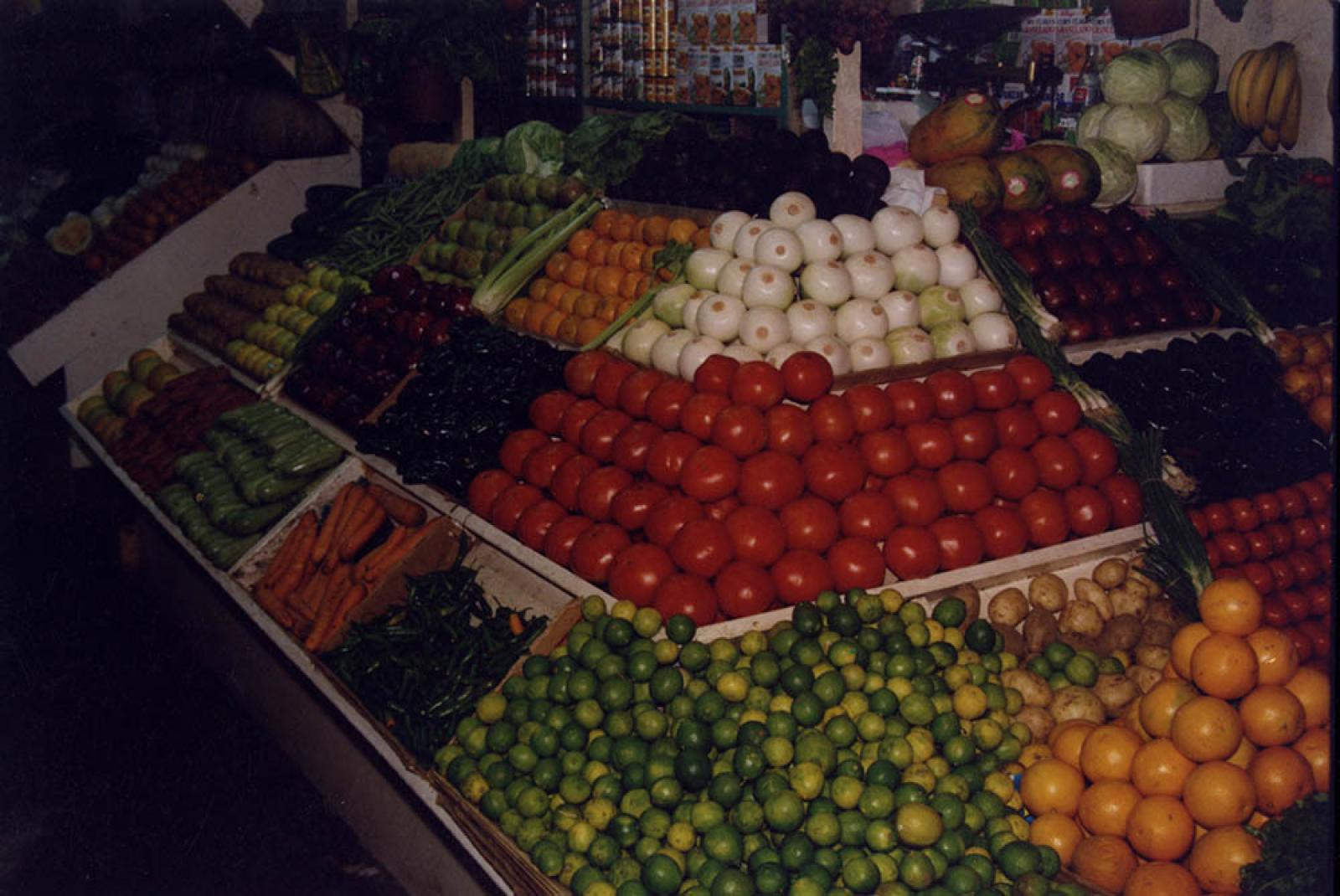 Puesto de frutas y verduras en interior de mercado.