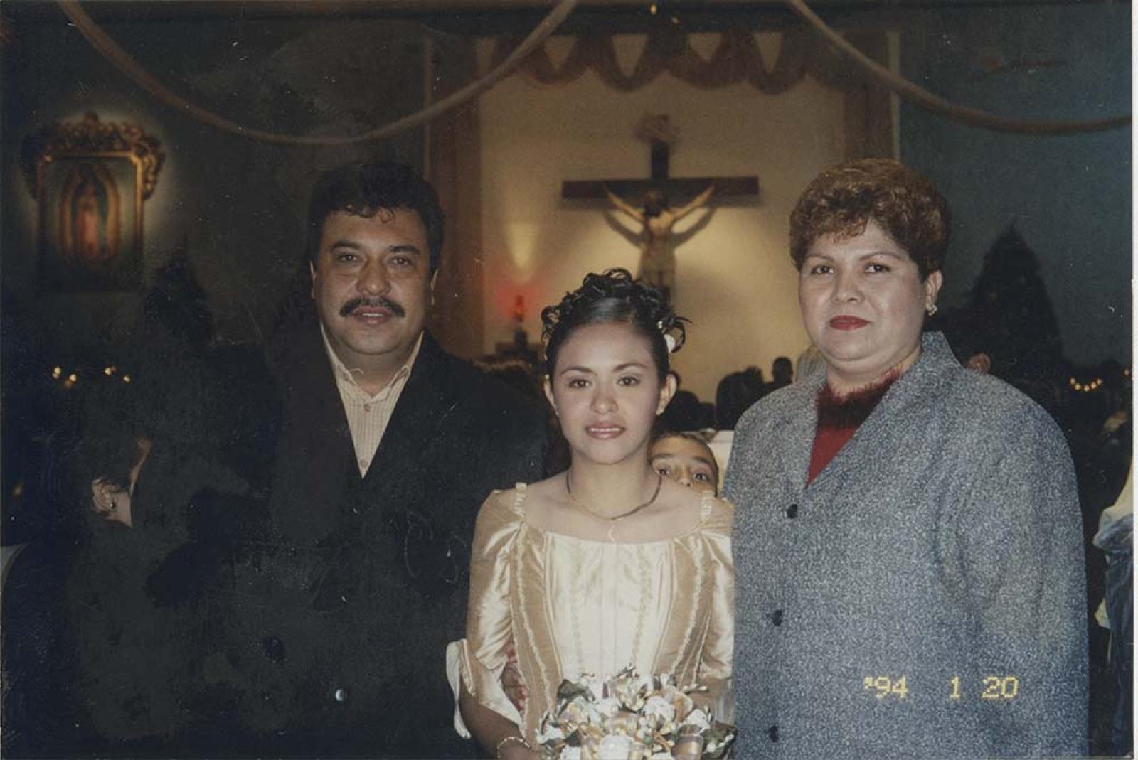 Quinceañera acompañada, en interior de iglesia.