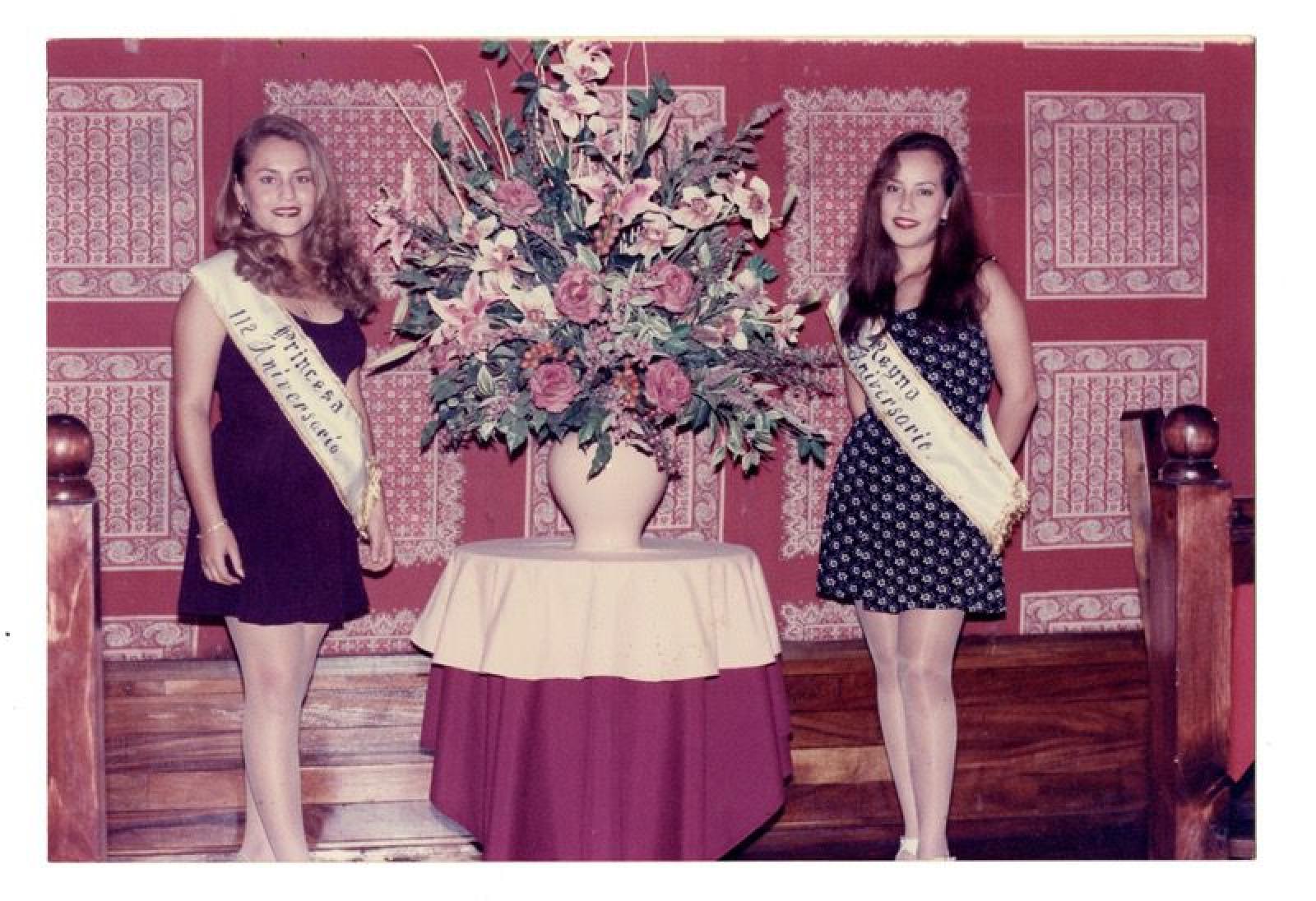 Reina y princesa junto a arreglo floral.