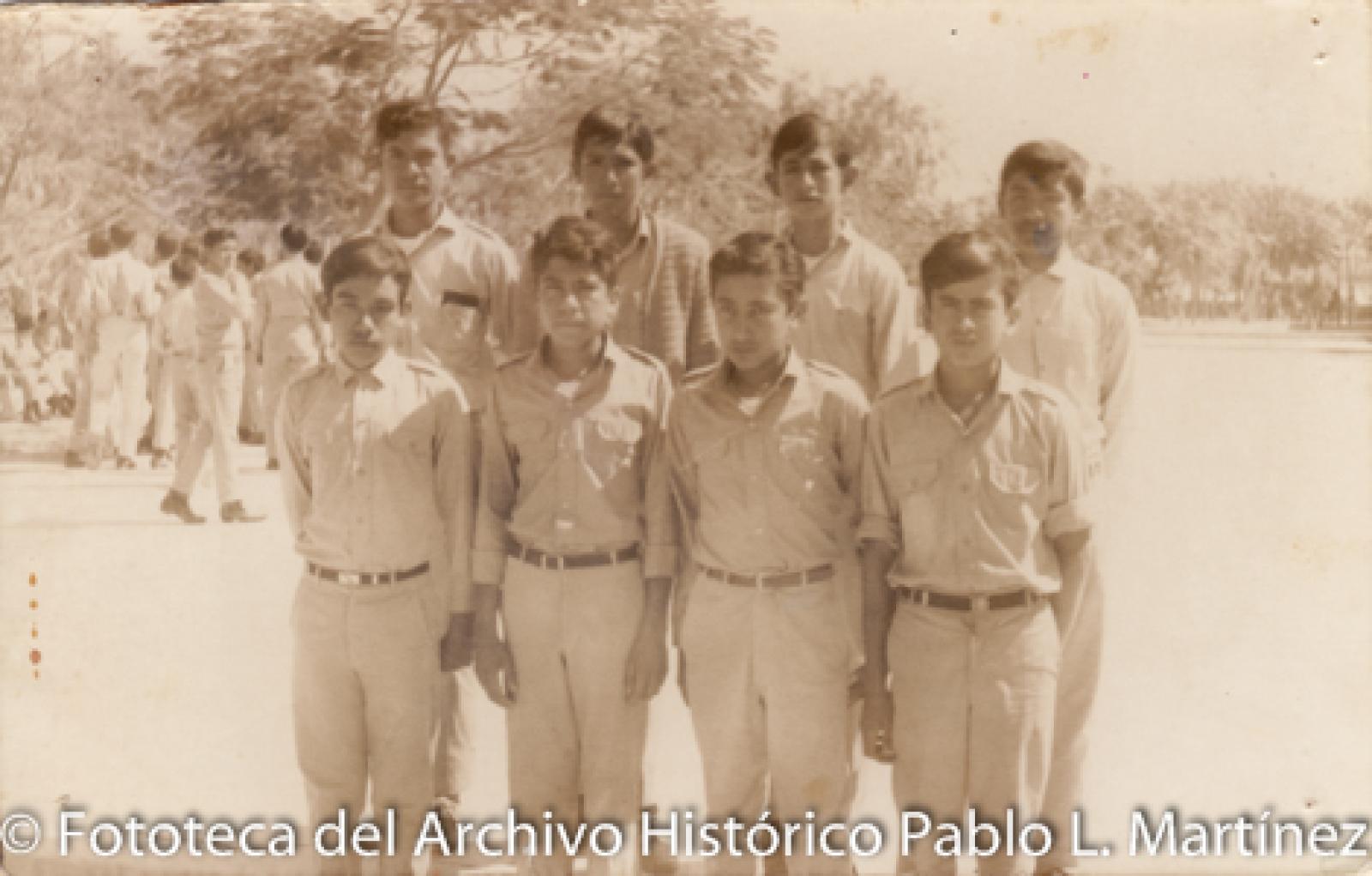 Retrato de grupo en patio con árboles.