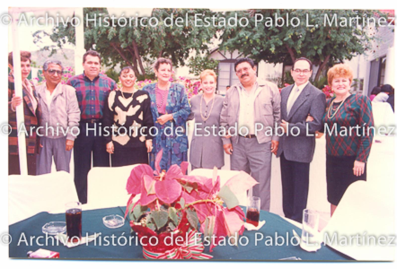 Retrato de hombres y mujeres atrás de una mesa preparada para un banquete.