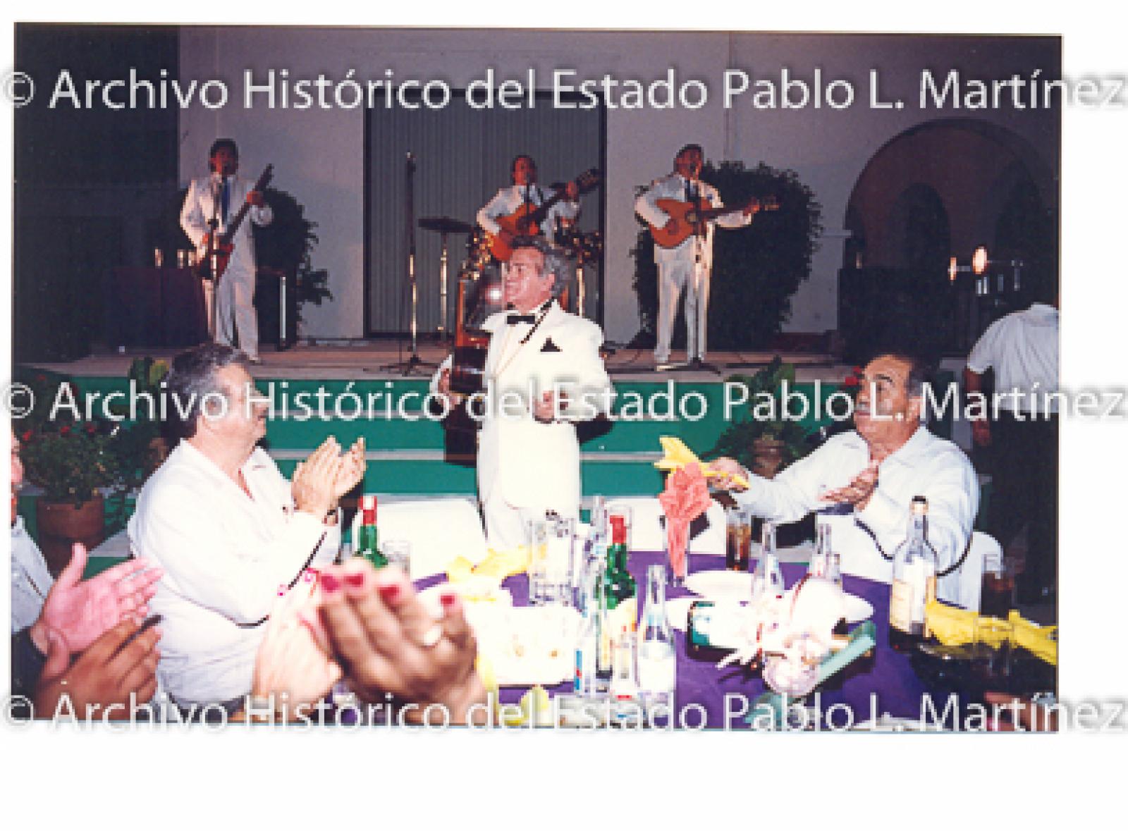 Señores en cena frente a músicos.