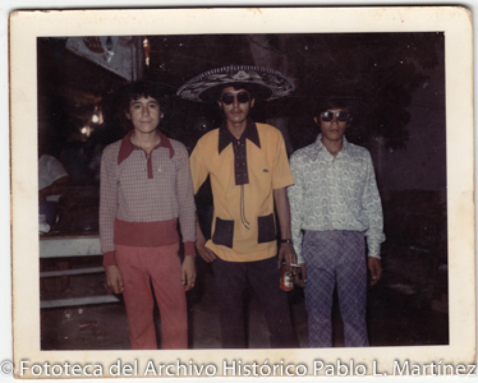 Tres hombres, uno con sombrero de charro