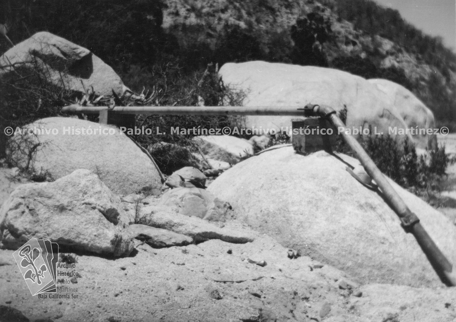 Tubería metálica de 3 pulgadas de diámetro, asegurada sobre dos grandes piedras en la margen derecha del arroyo de San Bartolo para la instalación de agua potable en San Bartolo, Baja California.