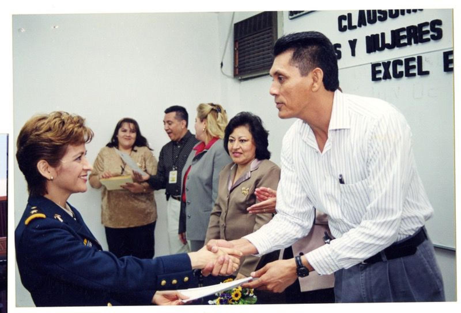 Valentín Castro Burgoin entrega documentos a mujer.
